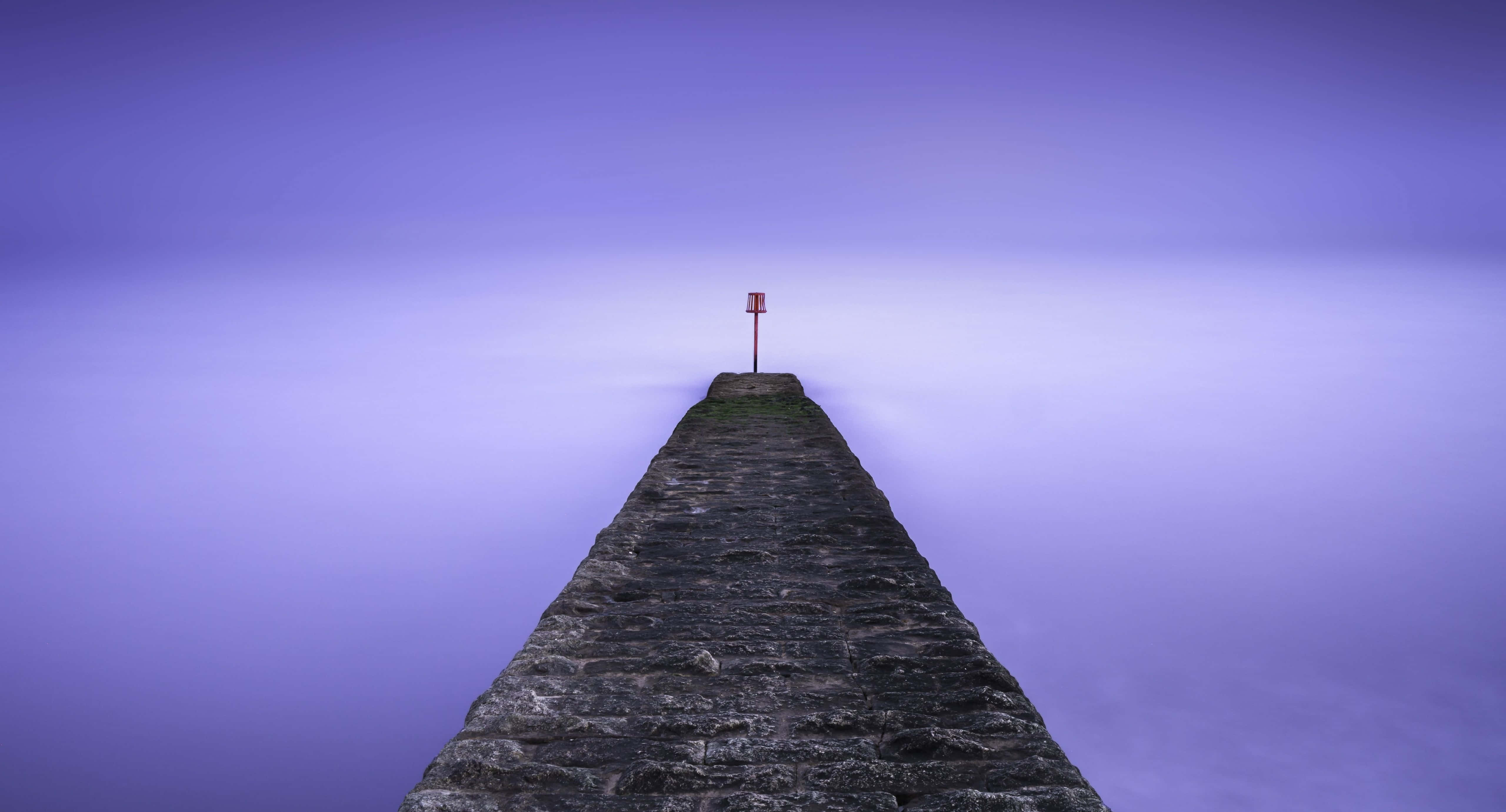 Calm Aesthetic Desktop 桌布 壁紙 — 一條孤獨的石碼頭延伸到霧濛濛的紫色大海中，盡頭有一個紅色標記。