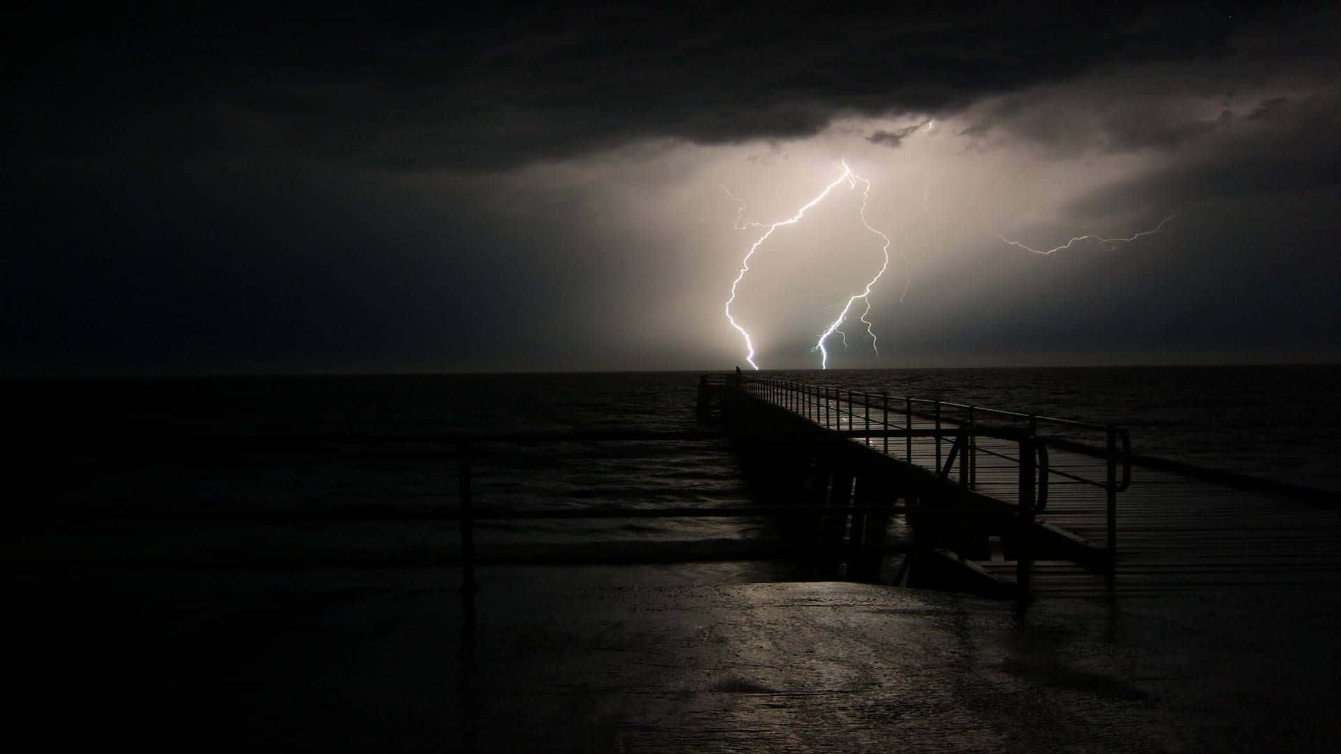 暴風 桌布 壁紙 — 一條孤獨的碼頭伸入暴風雨的海中，一道巨大的閃電照亮了上方的烏雲。