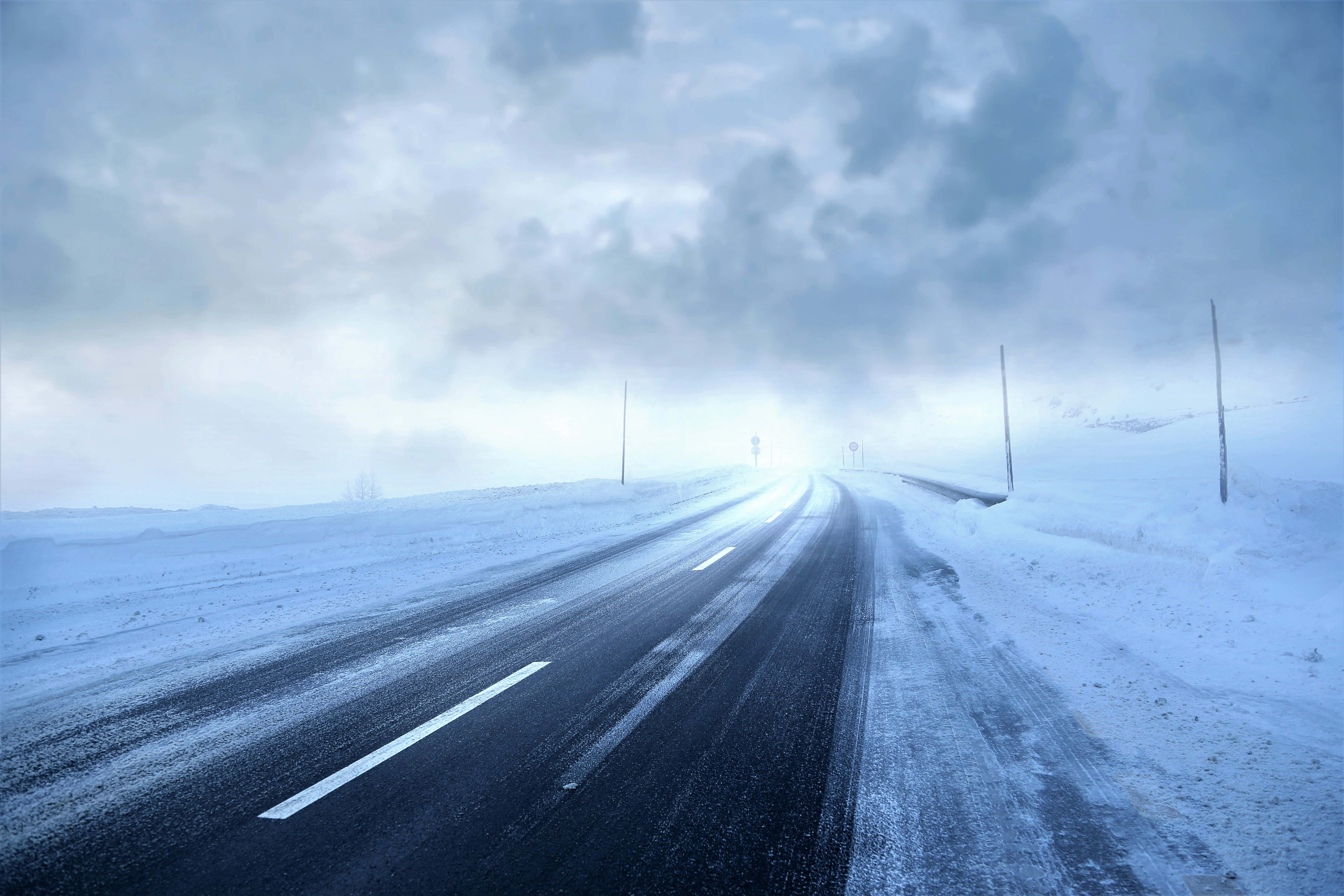 Snowstorm 桌布 壁紙 — 一條孤獨的積雪道路在陰天延伸至迷霧的冬季地平線。
