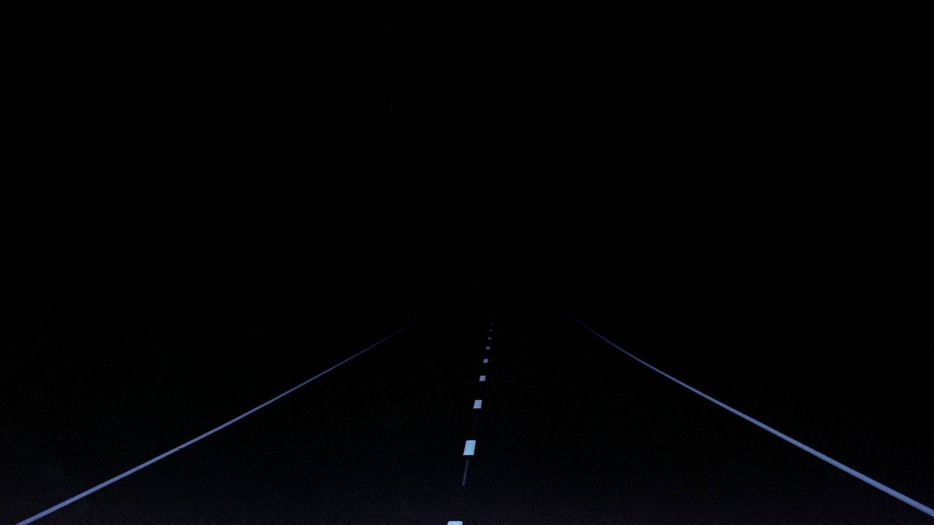 夜間黑暗的道路，發光的車道標記延伸至遠方