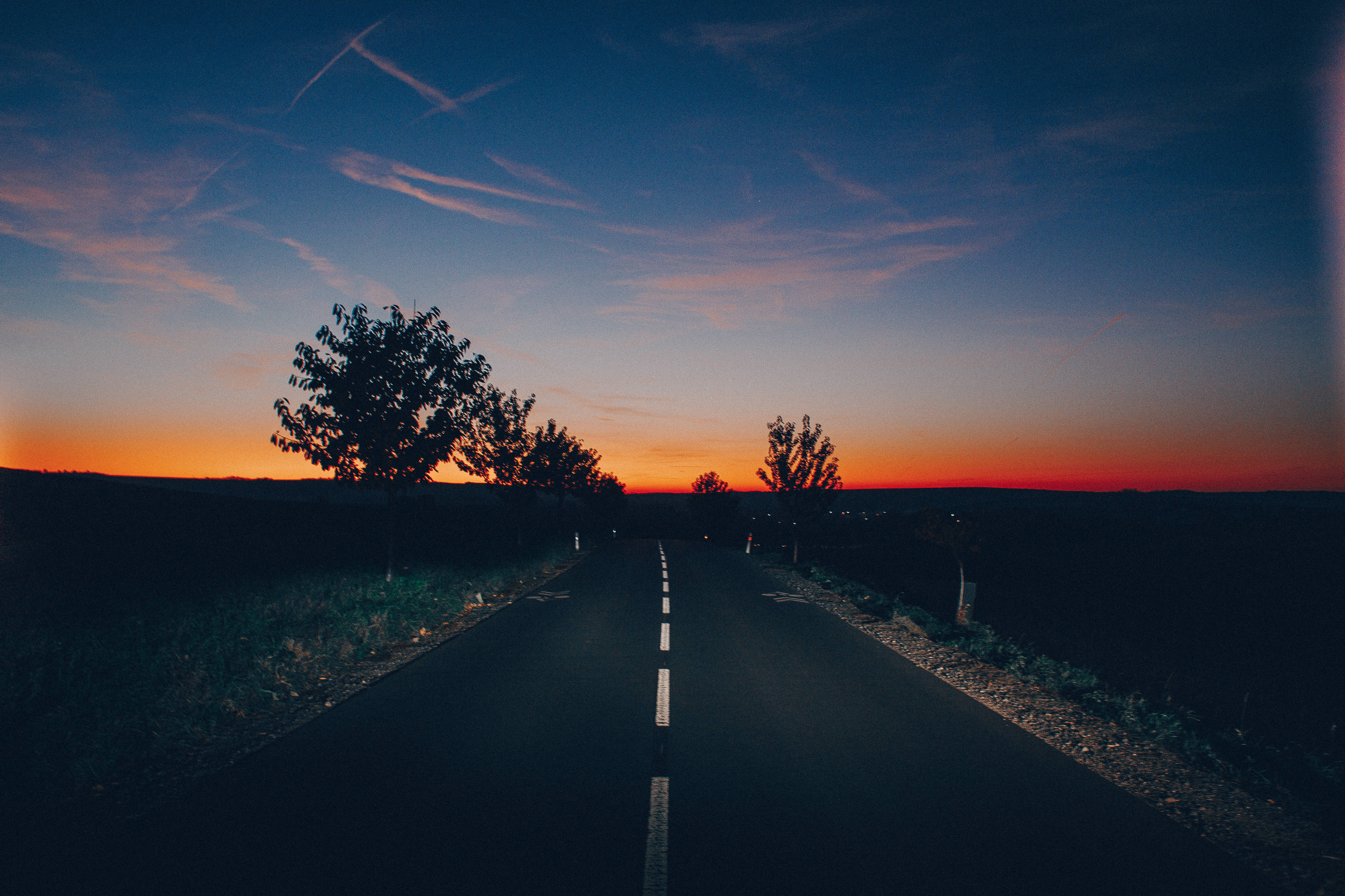 Aesthetic Sky 桌布 壁紙 — 一條孤獨的道路在暮色天空下延伸至地平線，天空染上熾熱的橙色和深藍色調。