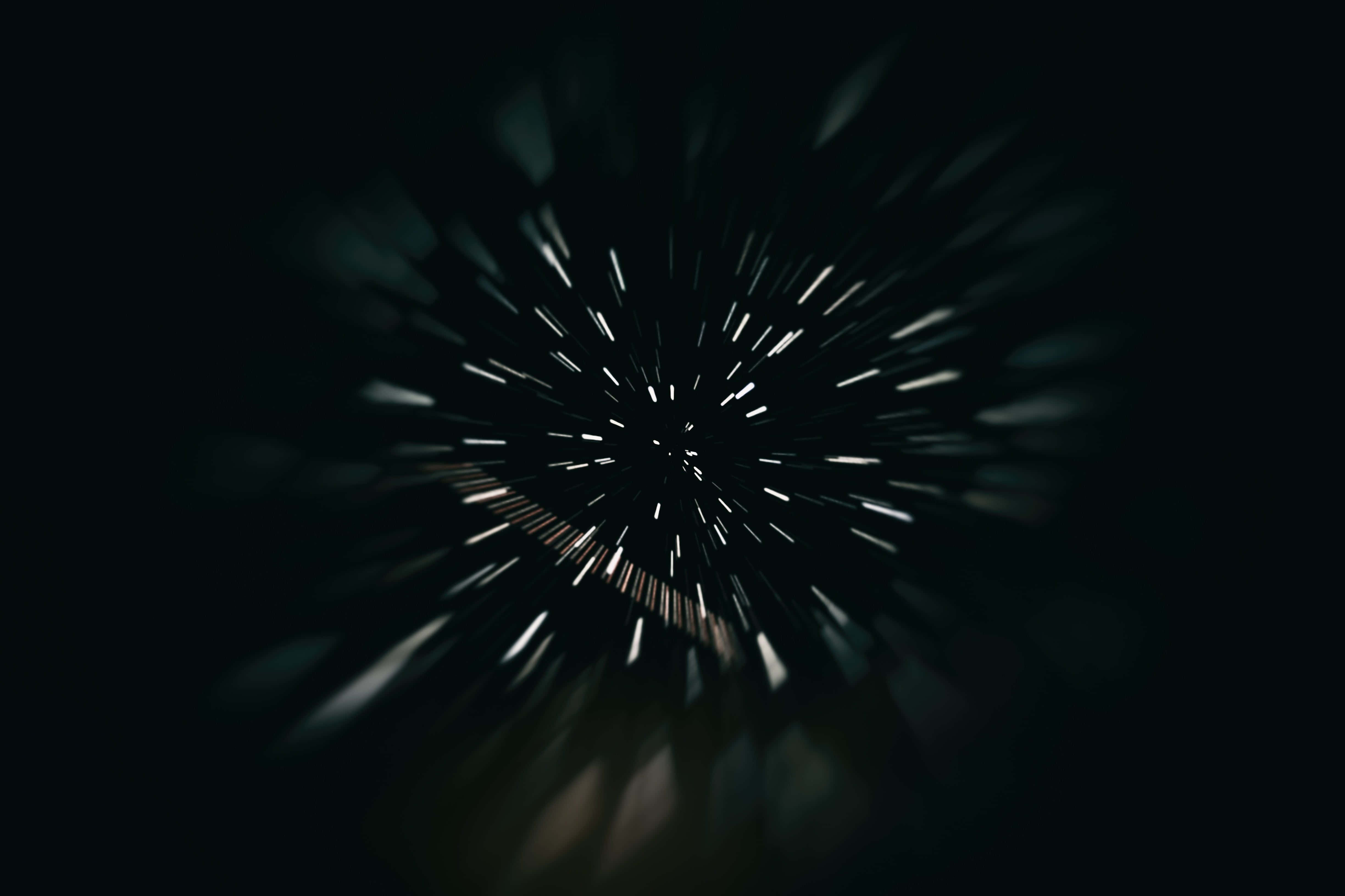 motion 桌布 壁紙 — 一條宇宙隧道，白色光芒從中心點向外輻射，背景是深邃的黑色虛空。