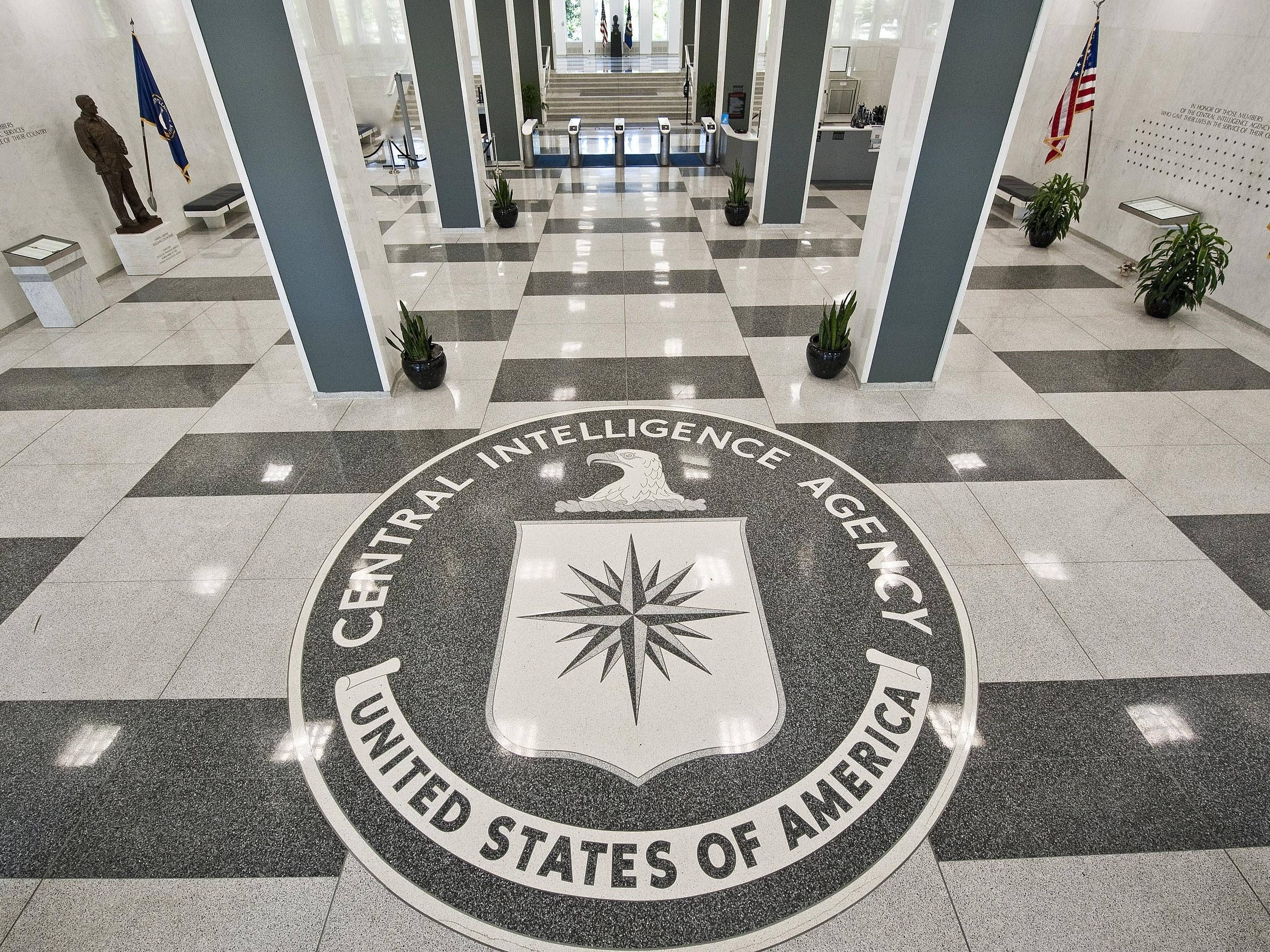 Cia 桌布 壁紙 — 一條宏偉的走廊，地板為棋盤格大理石，通向地板中央嵌入的大型CIA標誌。