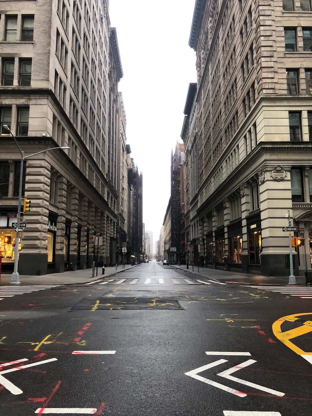 Street 桌布 壁紙 — 一條寧靜的城市街道，兩旁是高聳的石建築，褪色的街道標記在陰天之下。