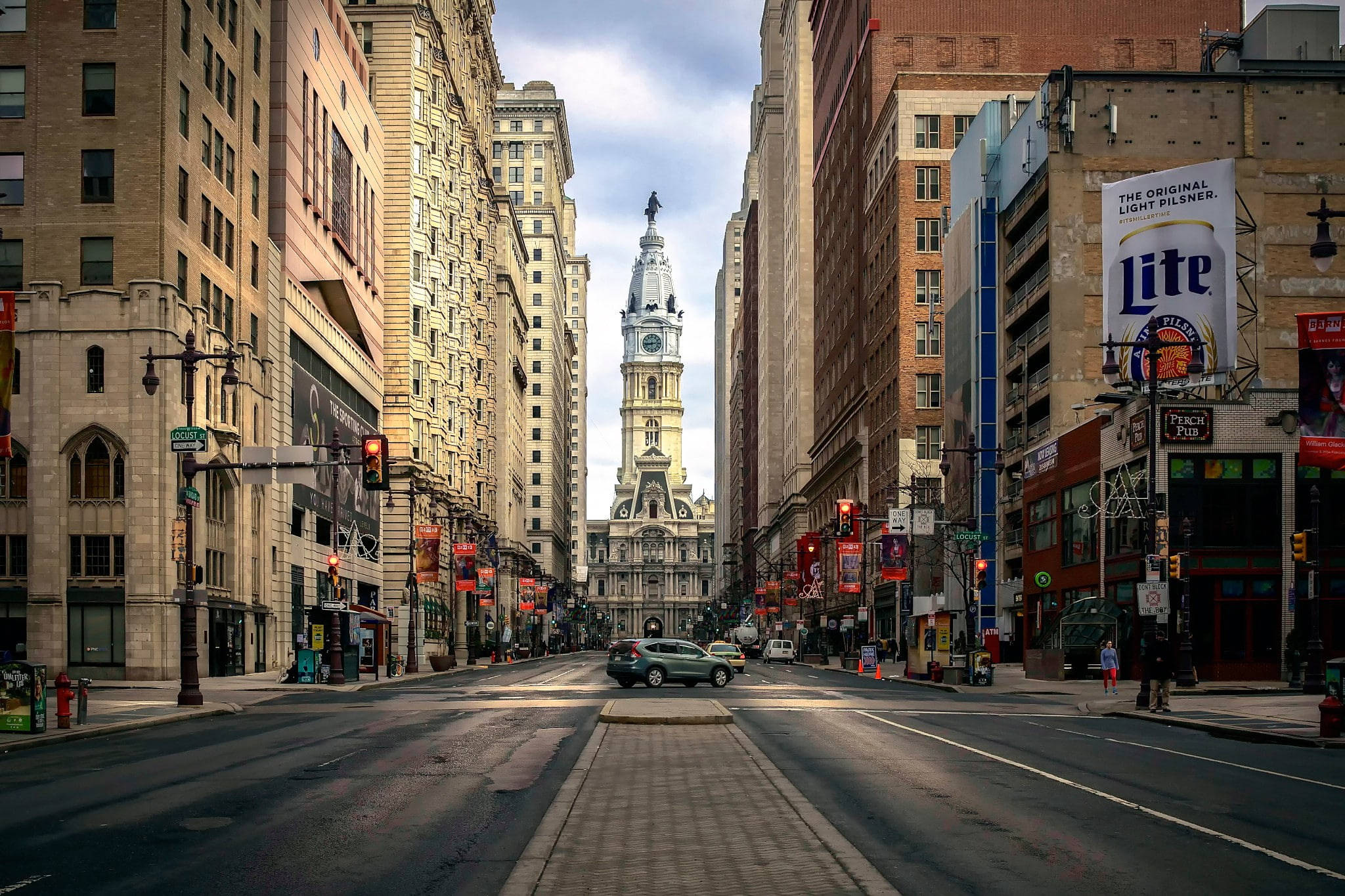 Philadelphia 桌布 壁紙 — 一條寬闊的城市街道，兩旁高樓大廈林立，通向一座歷史悠久的鐘樓，天空部分多雲。