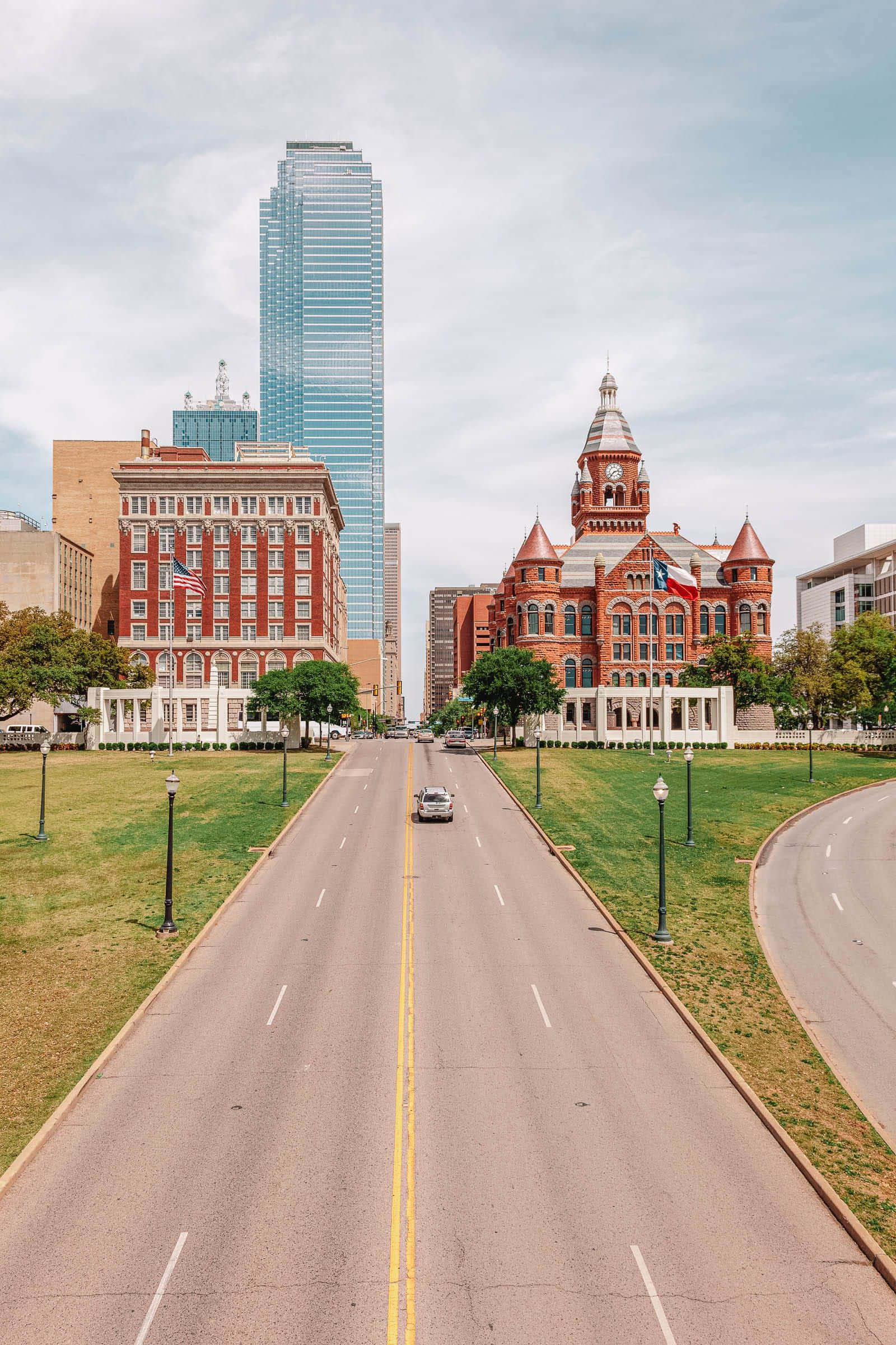 dallas 桌布 壁紙 — 一條寬闊的道路在陰天延伸向一座歷史悠久的紅磚法院和一座高聳的玻璃摩天大樓。