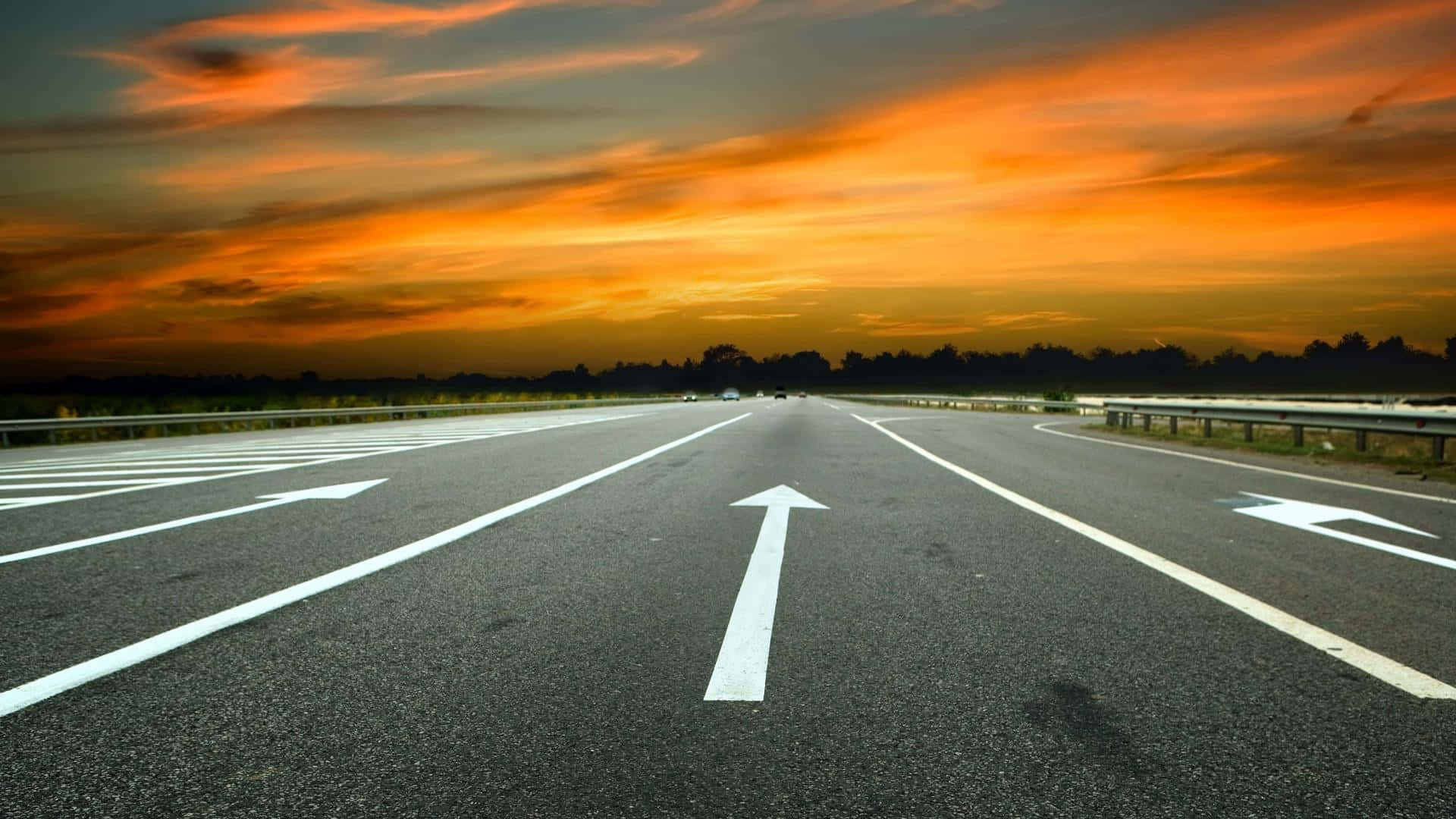 Highways 桌布 壁紙 — 一條寬闊的高速公路在火紅的橙色和紅色日落天空下延伸至地平線。