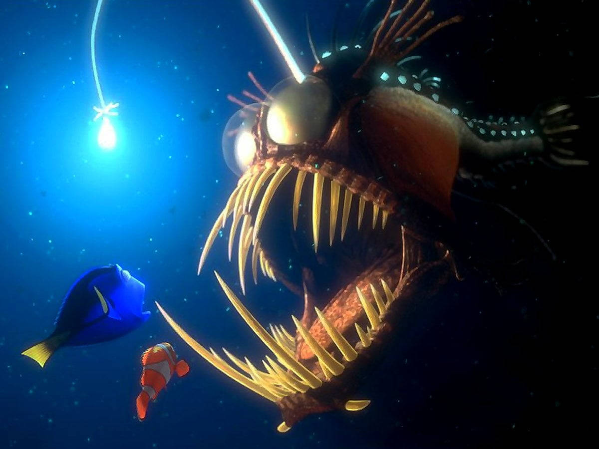 nemo 桌布 壁紙 — 一條巨型琵琶魚，帶有發光的誘餌和鋒利的牙齒，在深海黑暗中籠罩著小丑魚和藍色刺尾魚。