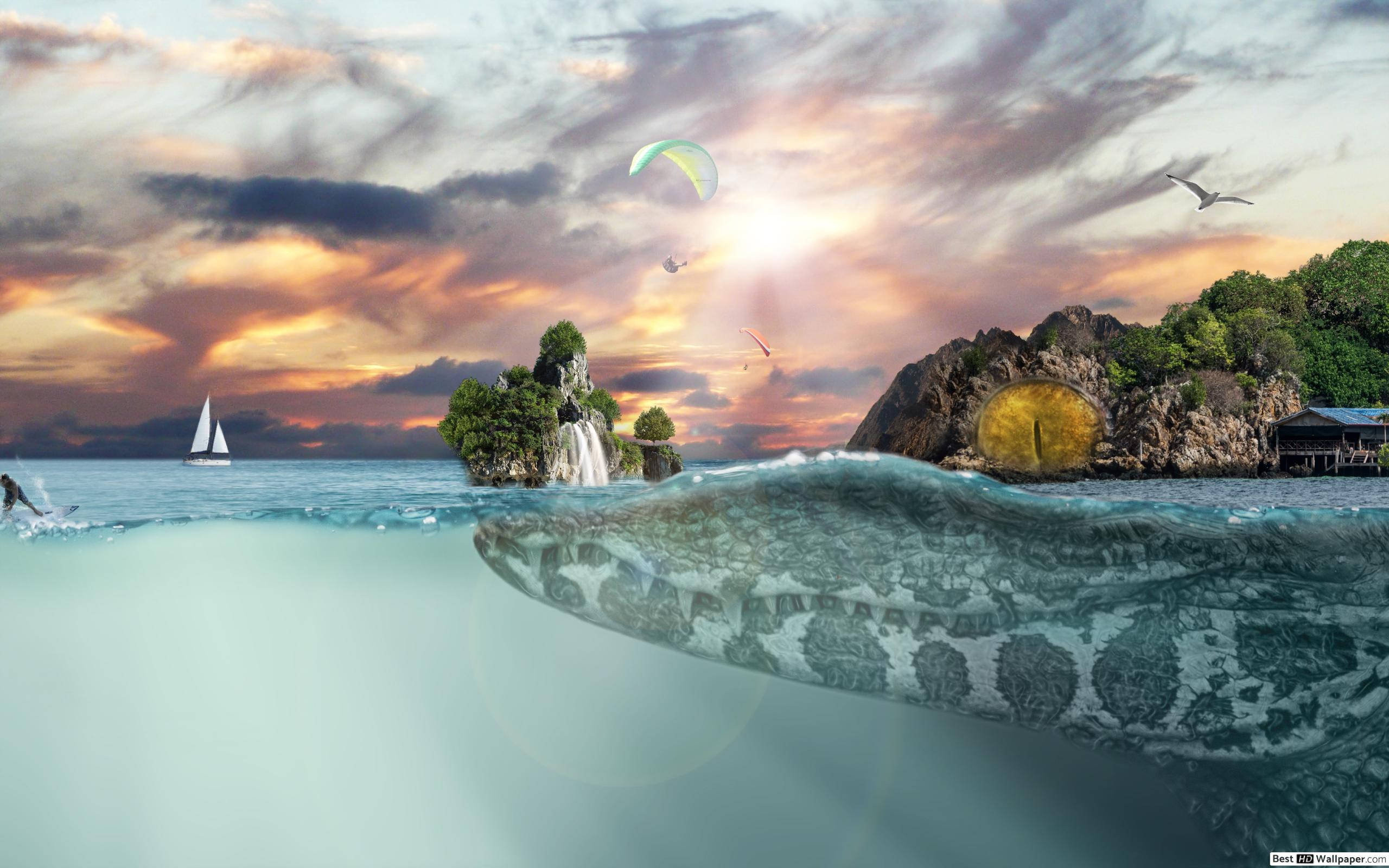 奇幻島 桌布 壁紙 — 一條巨大的海蛇從碧綠的海水中浮現，在 vibrant 的日落天空下，有帆船和滑翔傘在岩石島嶼上空。