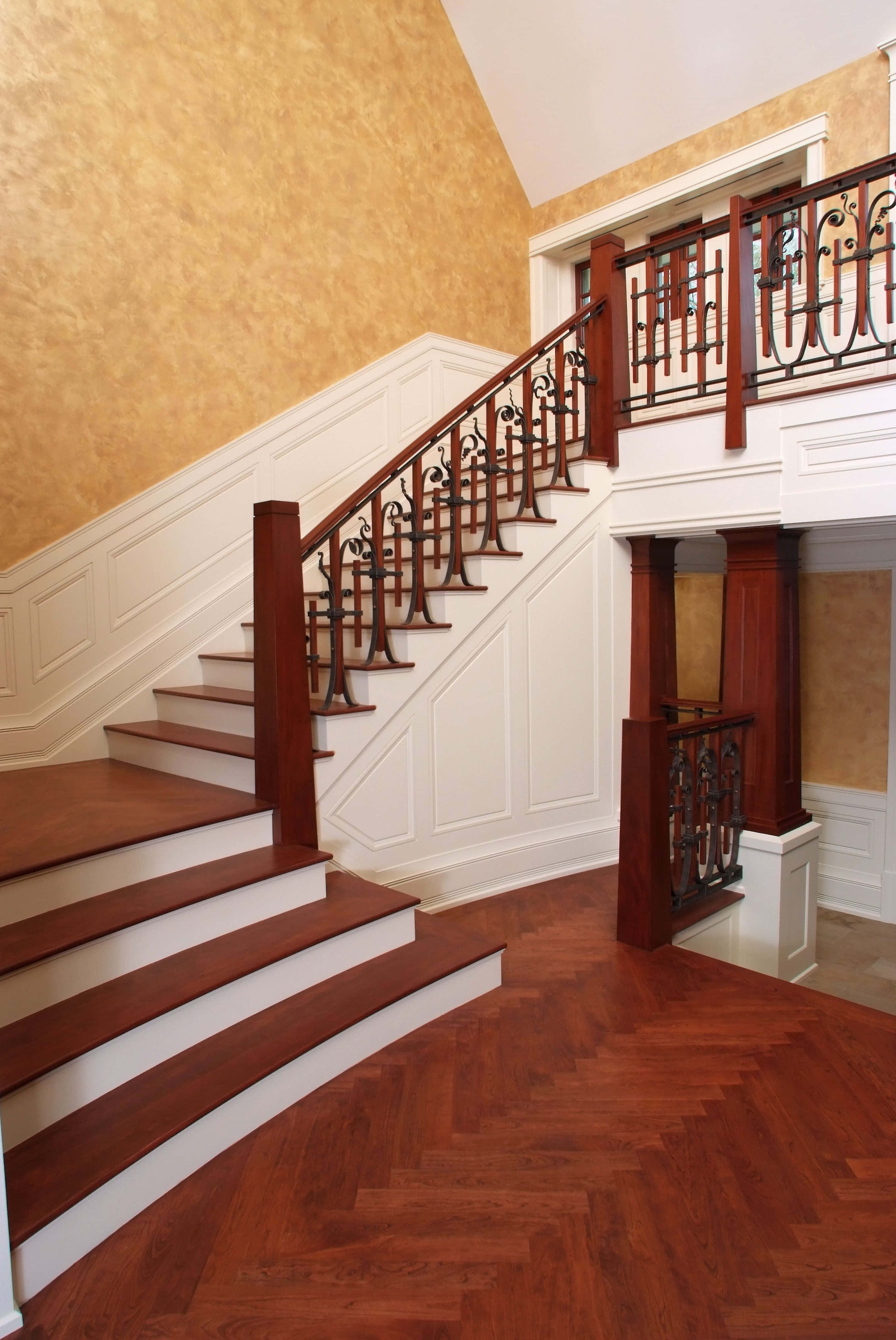 stairs 桌布 壁紙 — 一條帶有華麗鐵欄杆的宏偉木樓梯，穿過擁有魚骨紋地板和紋理金牆的豪華住宅向上延伸。