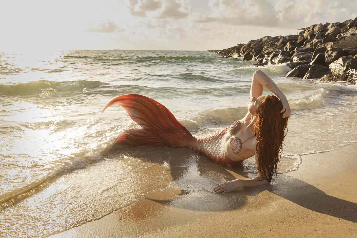 Mermaids 桌布 壁紙 — 一條擁有鮮豔橙色尾巴的美人魚躺在陽光明媚的海灘上，溫柔的海浪輕拍著她的沙灘。