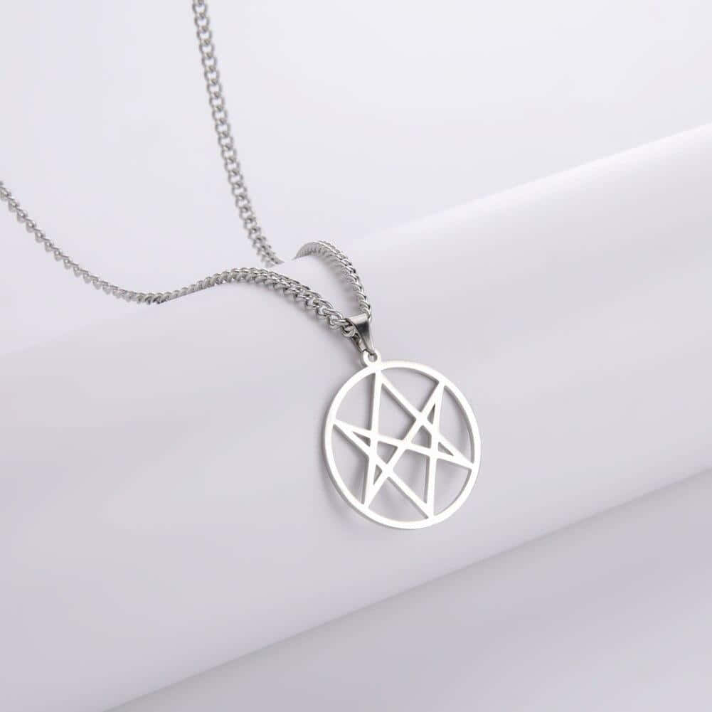 Thelema 桌布 壁紙 — 一條時尚的銀色五角星吊墜項鍊放在柔軟的白色表面上，以極簡優雅捕捉光線。