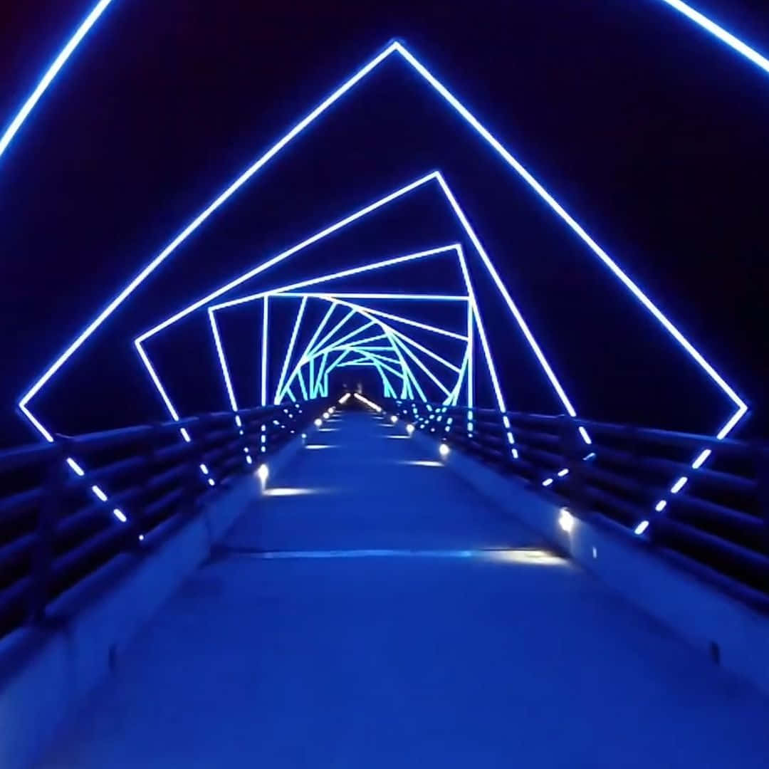 bridge 桌布 壁紙 — 一條未來主義的藍色霓虹燈行人天橋隧道，幾何三角形框架向遠方延伸。