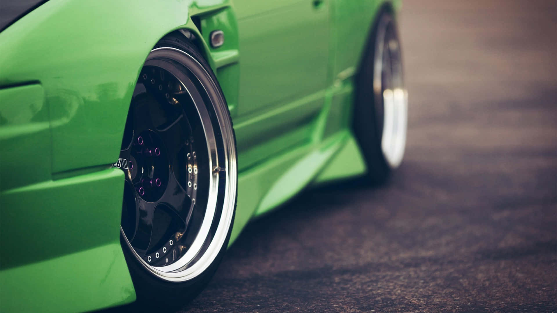 JDM 桌布 壁紙 — 一條柏油路上鮮綠色改裝車的車輪和擋泥板特寫。