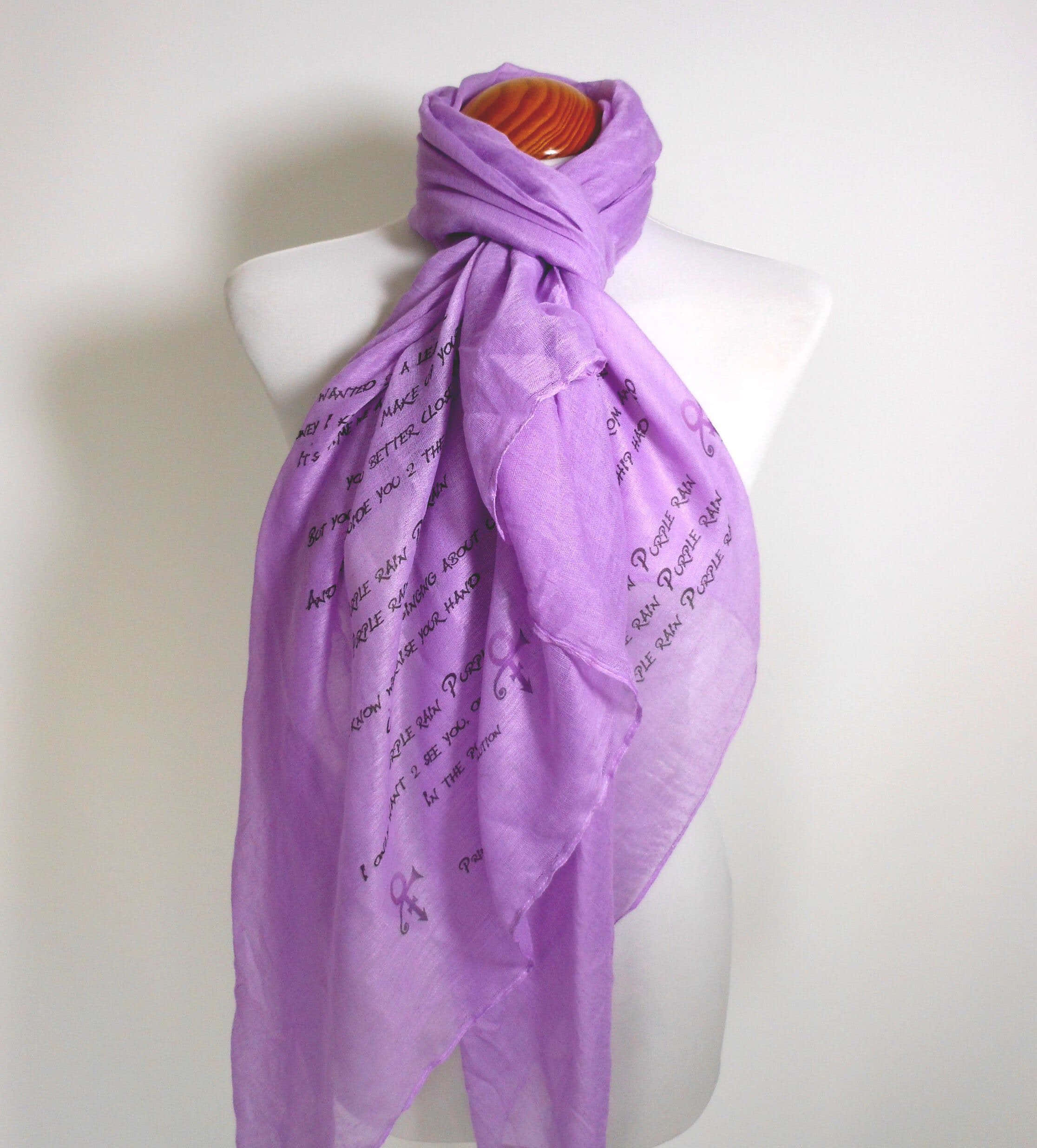 Purple Scarf 桌布 壁紙 — 一條柔軟的薰衣草色圍巾，上面有手寫文字和紫色絲帶圖案，優雅地披在白色人體模型上，背景是純白色。