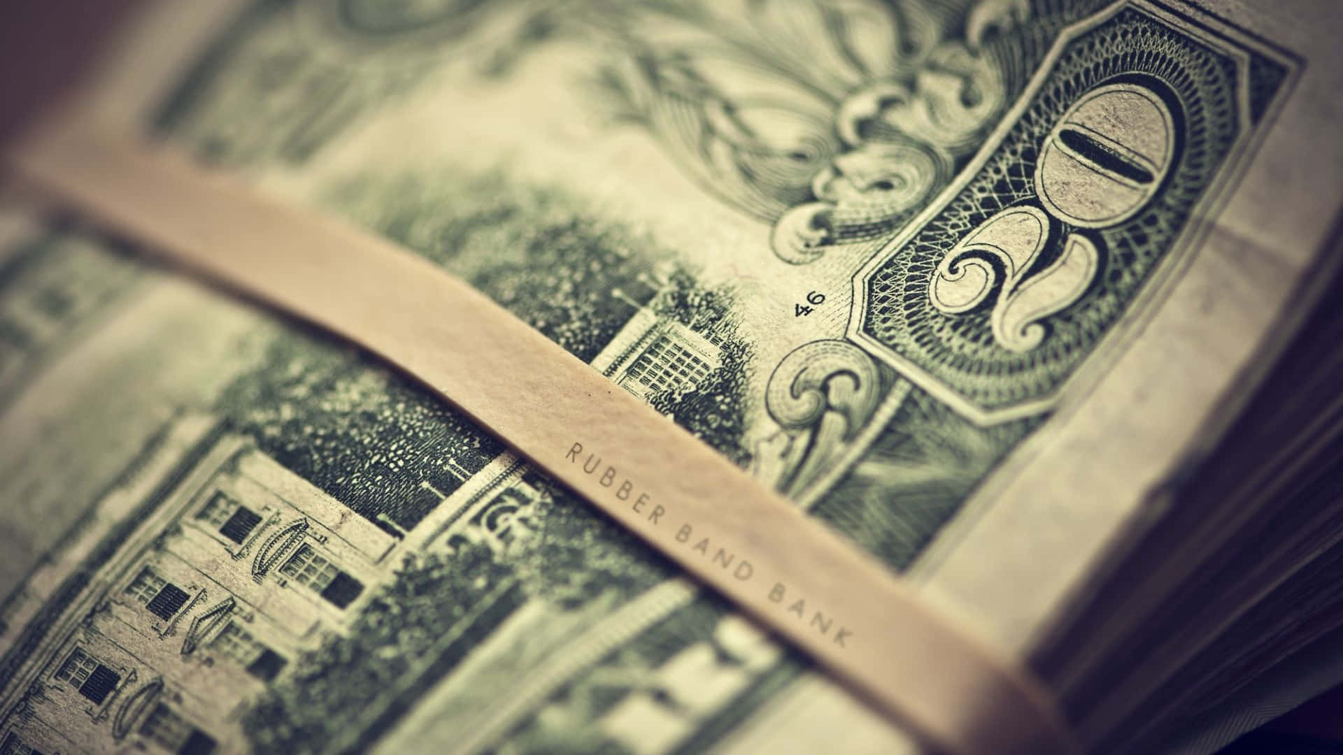 金錢 桌布 壁紙 — 一條標有「RUBBER BAND BANK」的橡皮筋束住一疊帶有華麗雕刻的復古綠色美元鈔票的特寫。