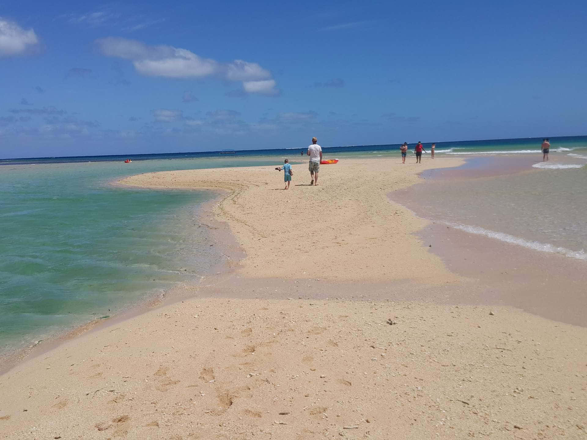 Fiji Beach 桌布 壁紙 — 一條沙嘴在碧綠海水之間延伸，上方是晴朗藍天，白雲點綴。