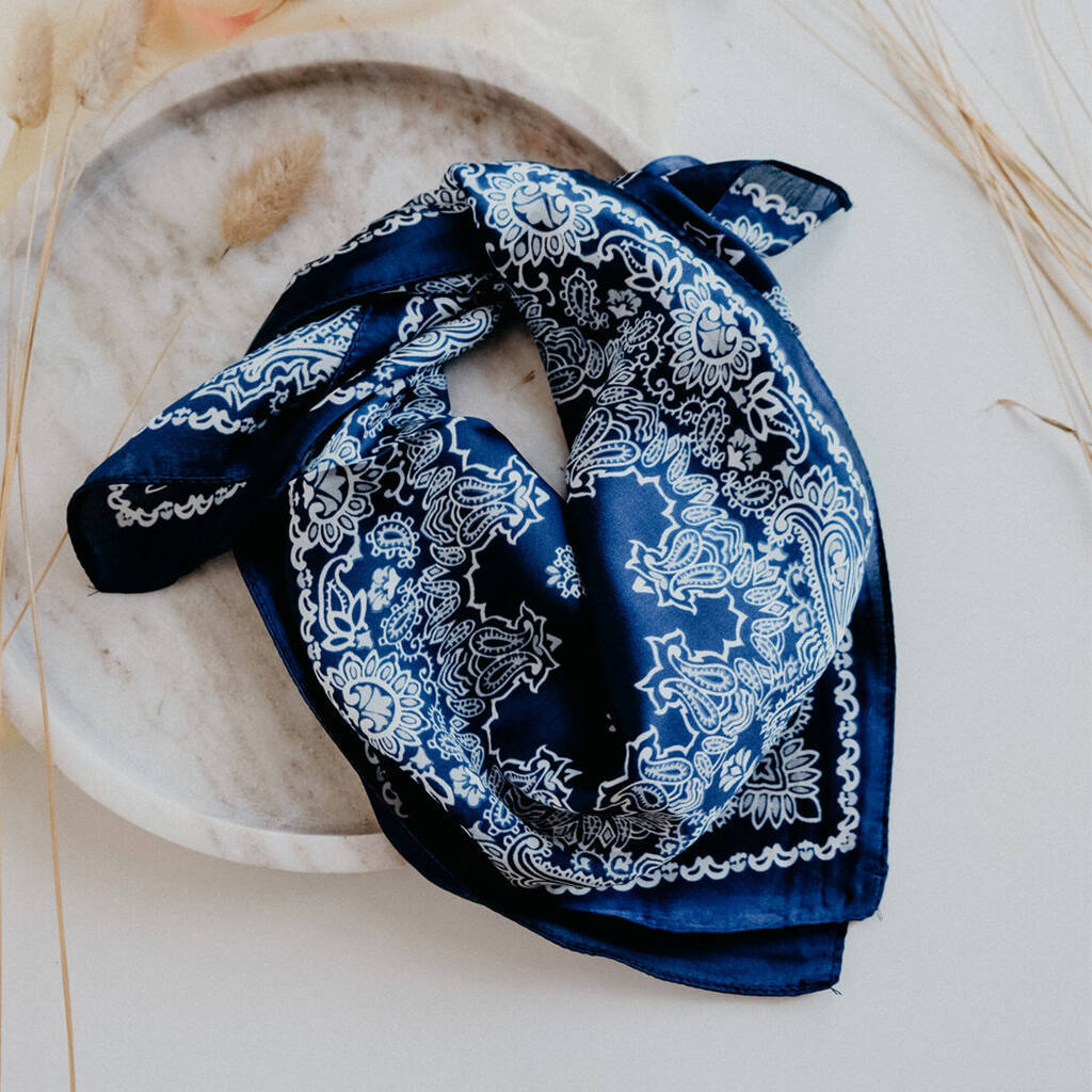 bandana 桌布 壁紙 — 一條海軍藍色班丹納巾，帶有精緻的白色佩斯利花紋，優雅地放置在一個被乾草圍繞的大理石盤子上。