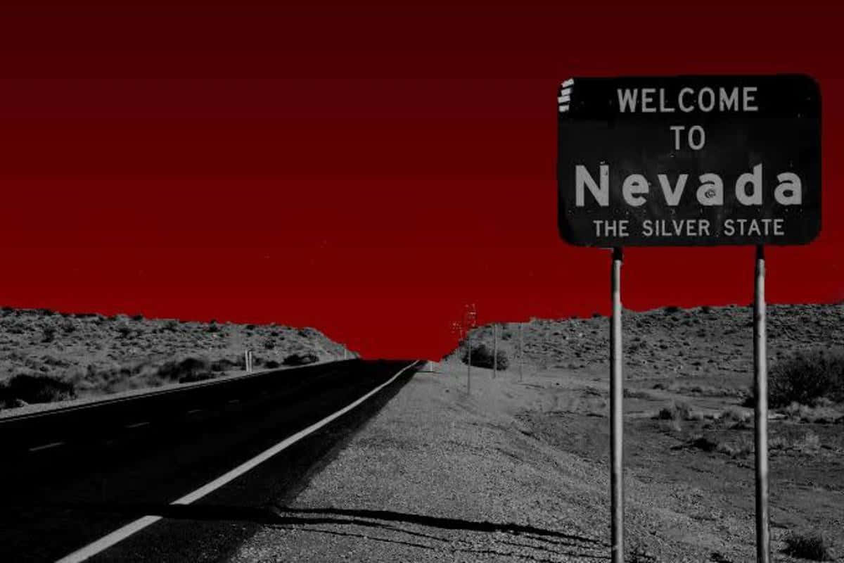Nevada 桌布 壁紙 — 一條清晰的黑白沙漠公路，在「歡迎來到內華達」標誌下，向著鮮紅色的天空延伸。