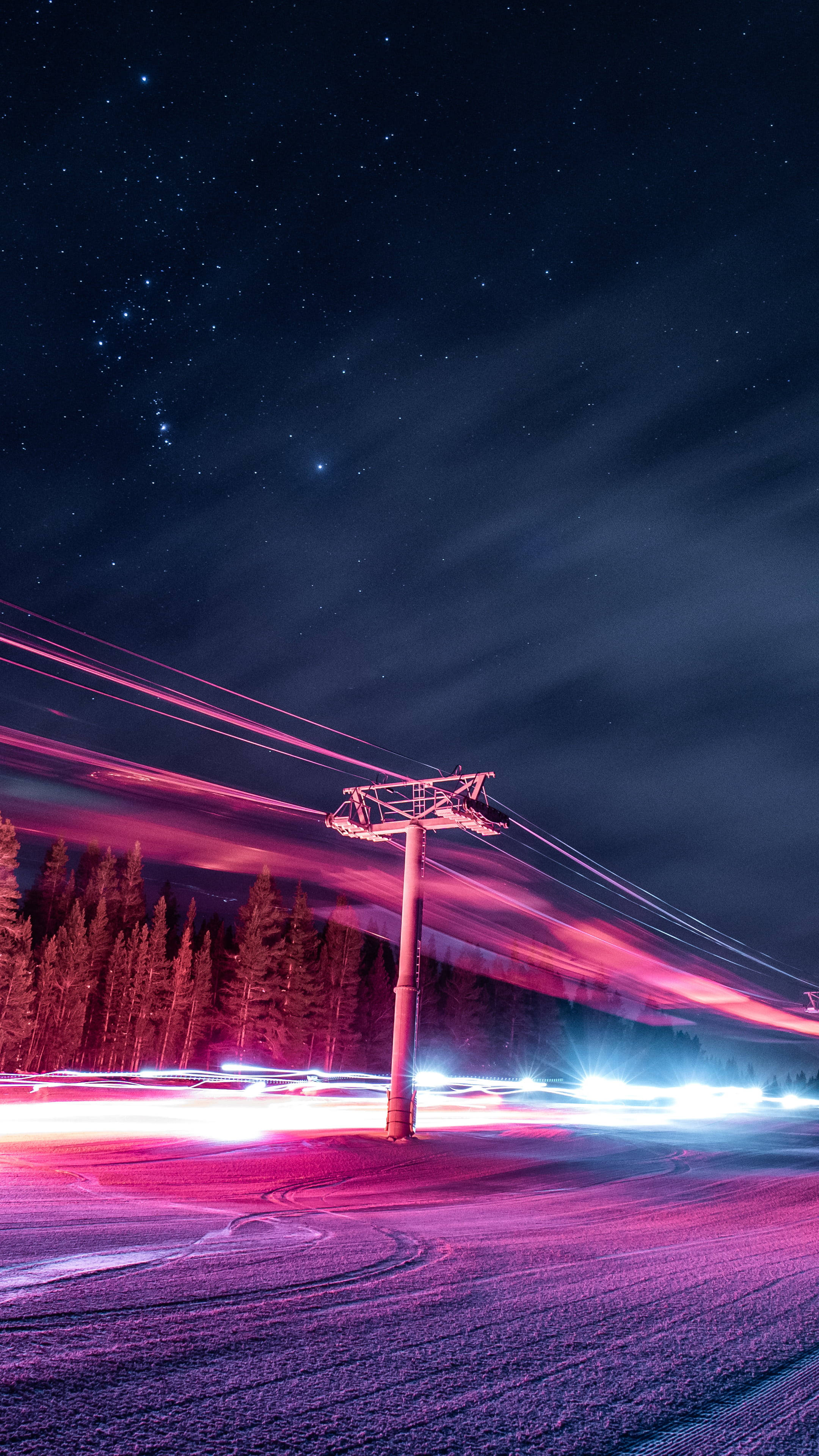 霓虹美學 桌布 壁紙 — 一條滑雪纜車柱矗立在繁星點點的夜空下，鮮豔的粉紅色和藍色光軌劃過白雪覆蓋的山景。