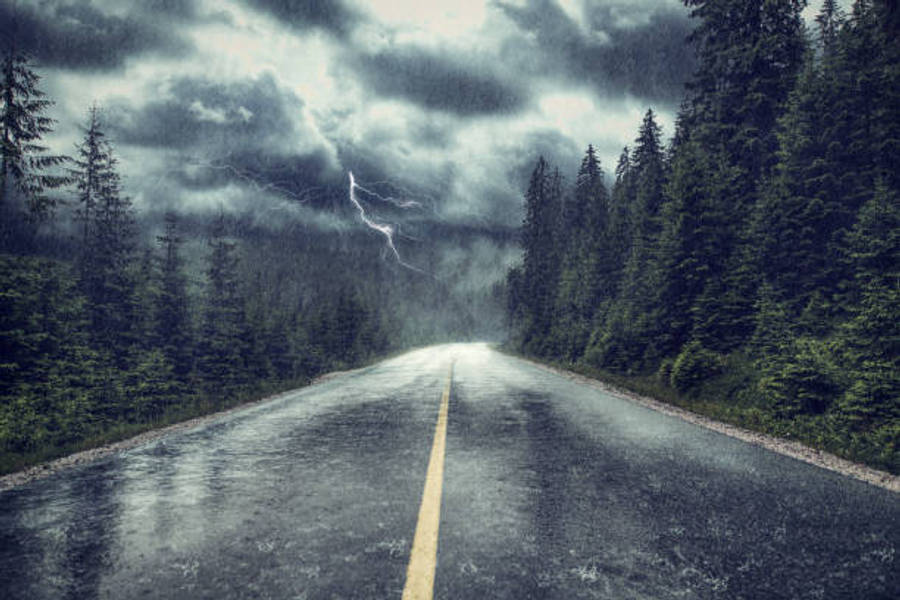 Wither Storm 桌布 壁紙 — 一條濕漉漉的瀝青路延伸進暴風雨中的森林，閃電在上方烏雲中分叉。