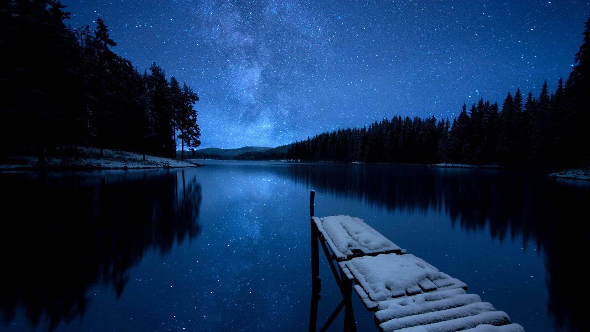 Starry 桌布 壁紙 — 一條灑滿雪花的木碼頭延伸至一個繁星點點的夜湖，湖面倒映著雪松林上空的銀河。