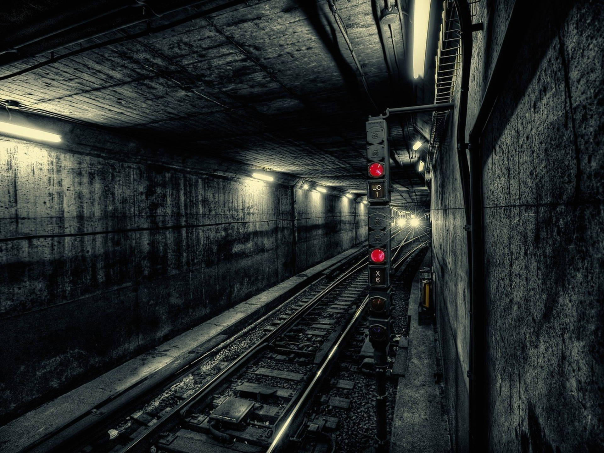 Subway 桌布 壁紙 — 一條燈光昏暗的地鐵隧道，混凝土牆壁和路軌在閃爍的螢光燈下伸向遠方。