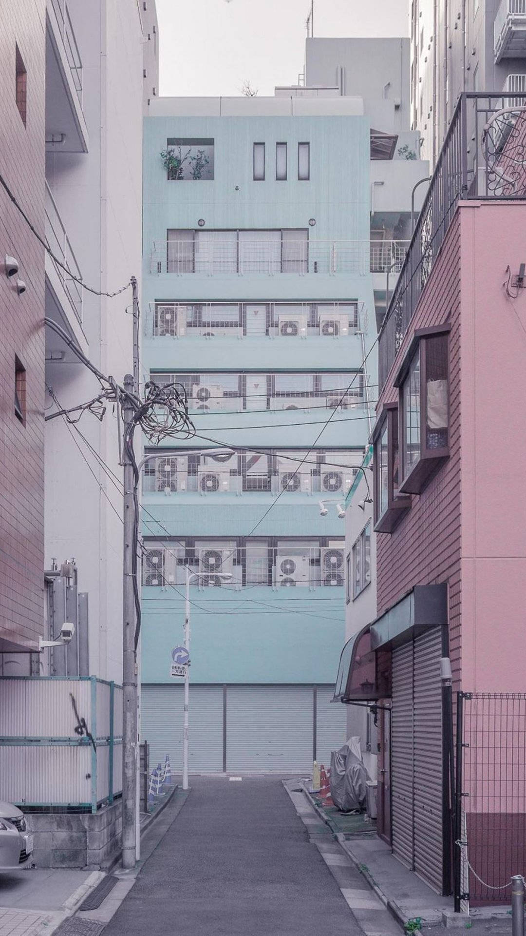pastel 桌布 壁紙 — 一條狹窄的城市小巷，兩旁是粉紅色和米黃色的建築，中央矗立著一棟粉藍色的公寓大樓。