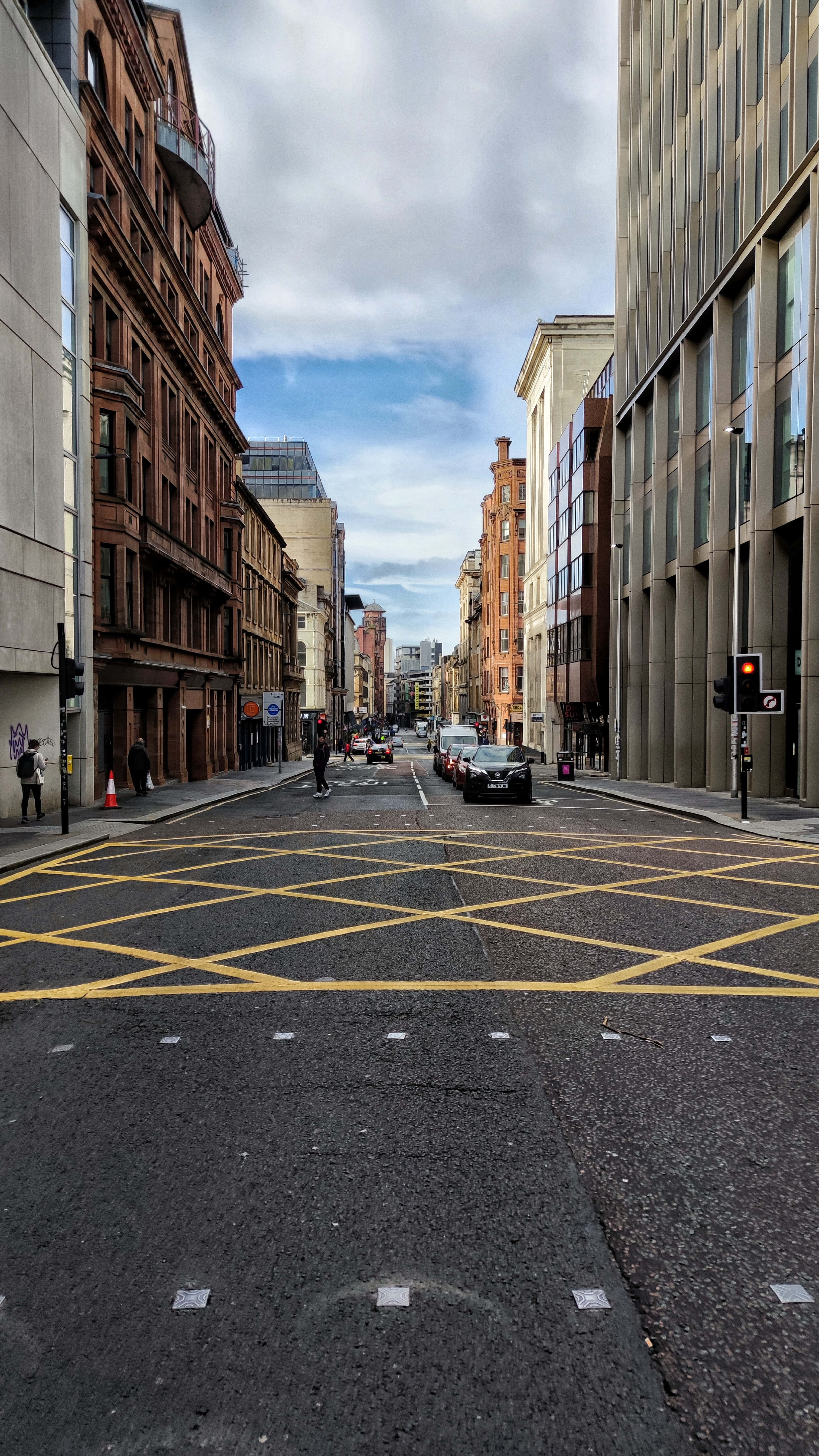 Street 桌布 壁紙 — 一條狹窄的城市街道，兩旁是歷史悠久的磚砌建築和現代玻璃幕牆，天空部分多雲。