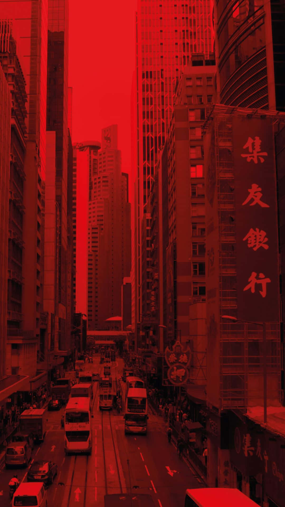 Aesthetic Red 桌布 壁紙 — 一條狹窄的城市街道，兩旁是高聳入雲的摩天大樓，沐浴在強烈的紅色單色光芒中。