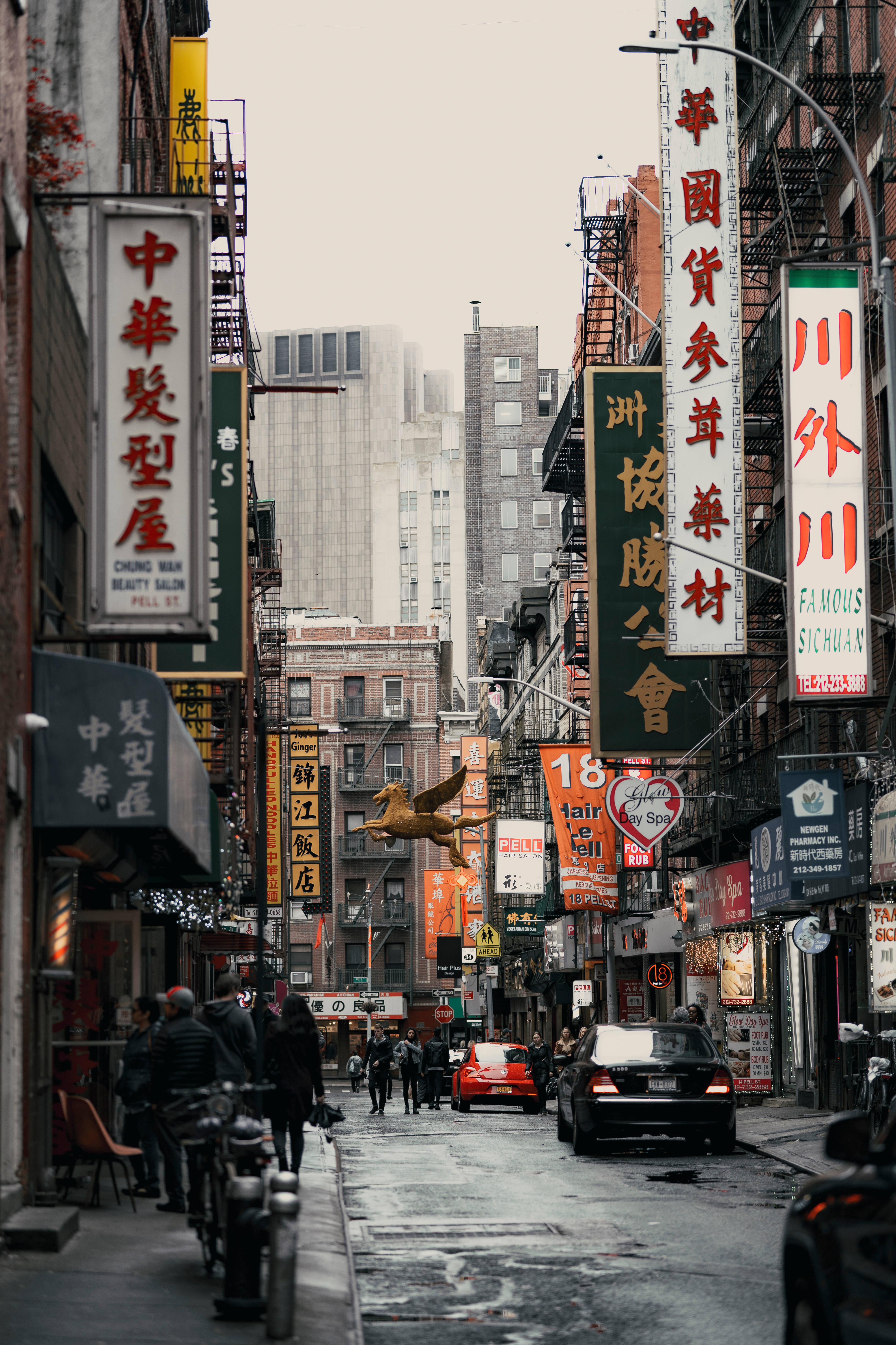 New 桌布 壁紙 — 一條狹窄的城市街道，兩旁是高聳的建築物和色彩繽紛的中文招牌，天空陰沉。