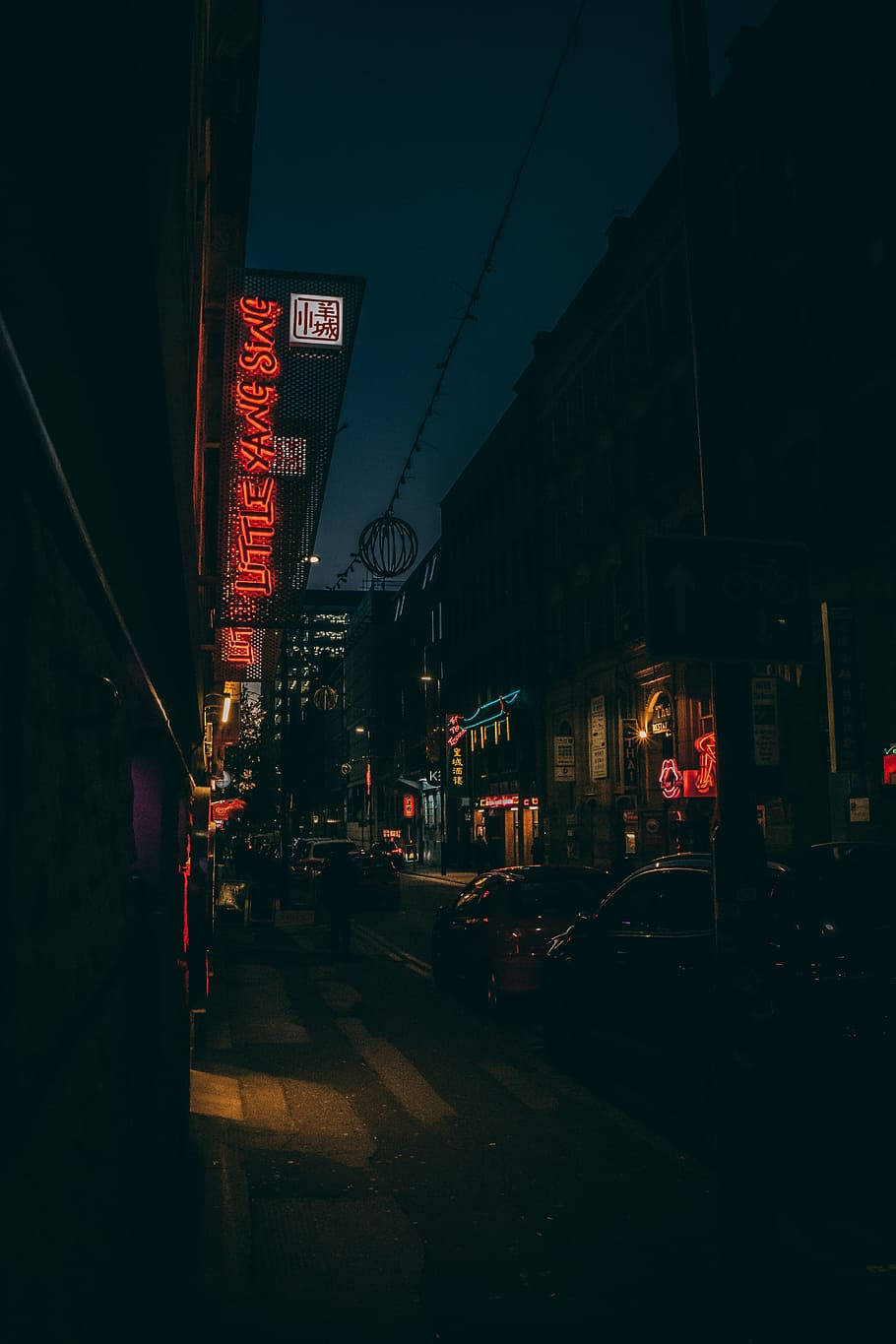 夜晚被紅色霓虹燈招牌和路燈照亮的黑暗城市街道。 — 黑暗城市 壁紙