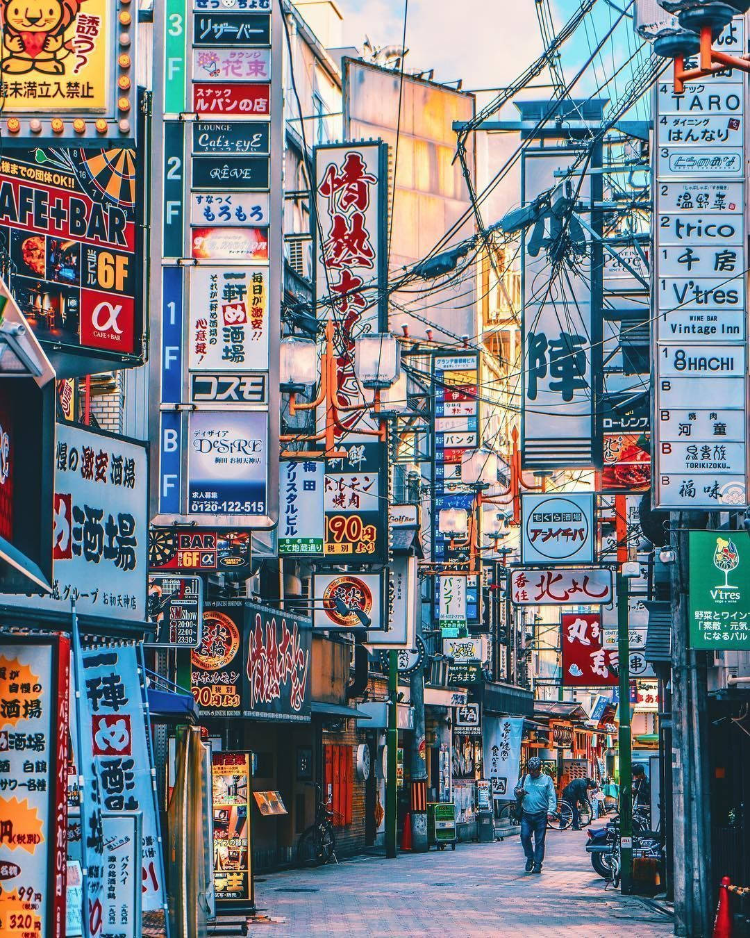 Japanese Aesthetic 桌布 壁紙 — 一條狹窄的東京小巷，沐浴在金黃色的日落光線中，擠滿了色彩繽紛的霓虹燈招牌和懸掛的電線。