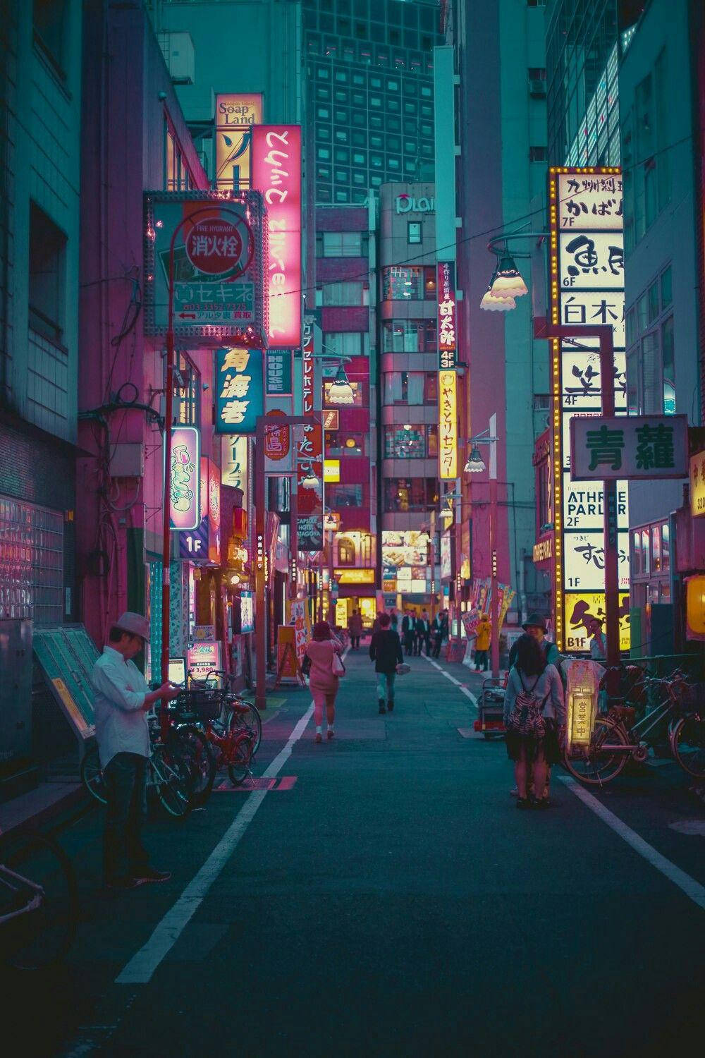 日本 桌布 壁紙 — 一條狹窄的東京小巷，被發光招牌和街燈的霓虹粉紅和藍色光芒所籠罩，行人漫步經過停放的腳踏車。