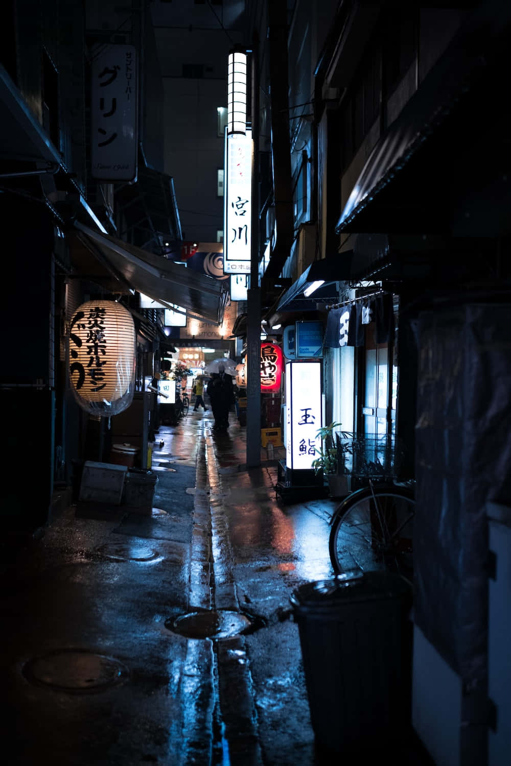 Dark Alleyway 桌布 壁紙 — 一條狹窄的雨夜東京小巷，被發光的霓虹燈招牌和燈籠照亮，倒映在濕漉漉的路面上。