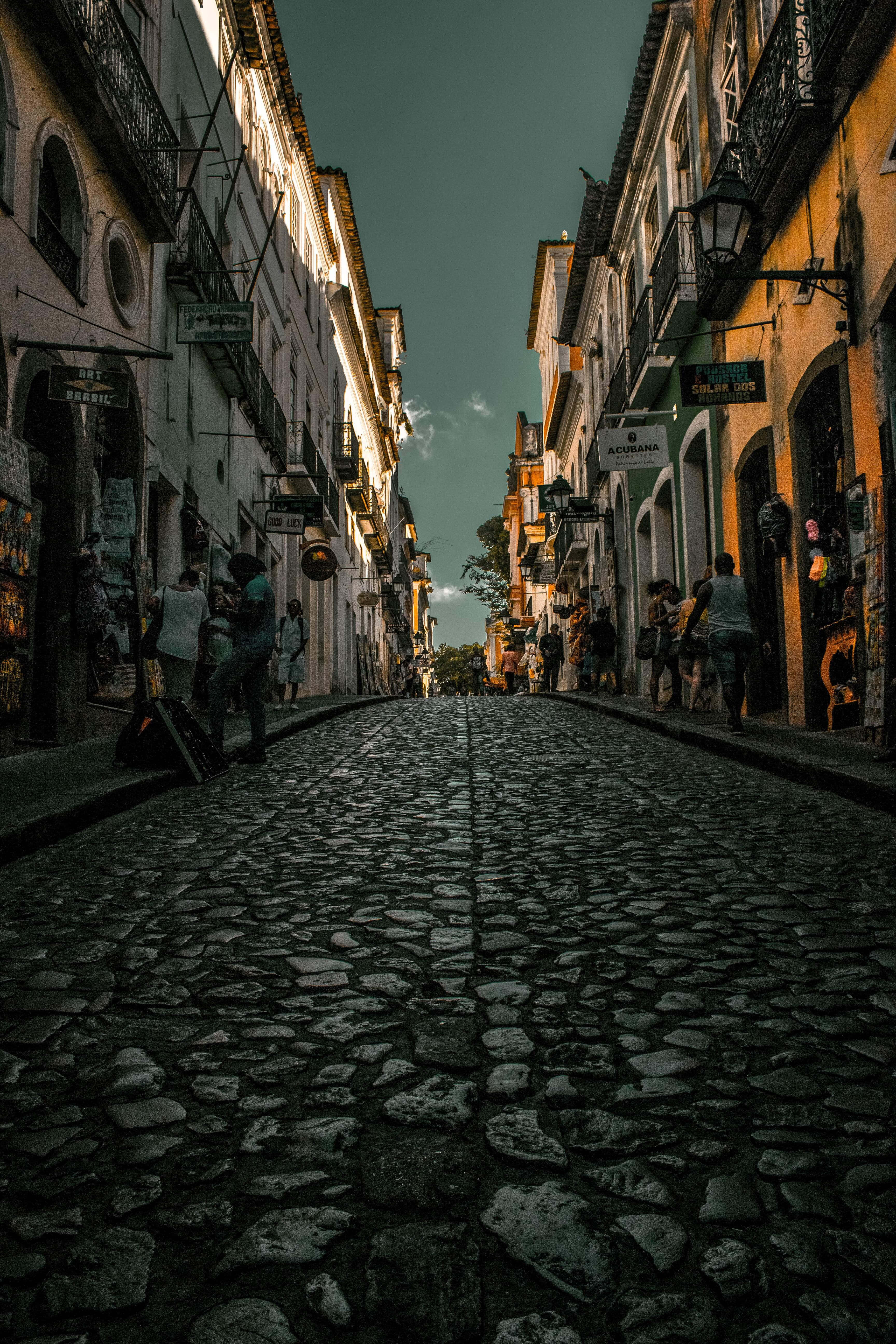 Cobblestone 桌布 壁紙 — 一條狹窄的鵝卵石街道，兩旁是色彩繽紛的殖民時期建築，在暮色天空下。