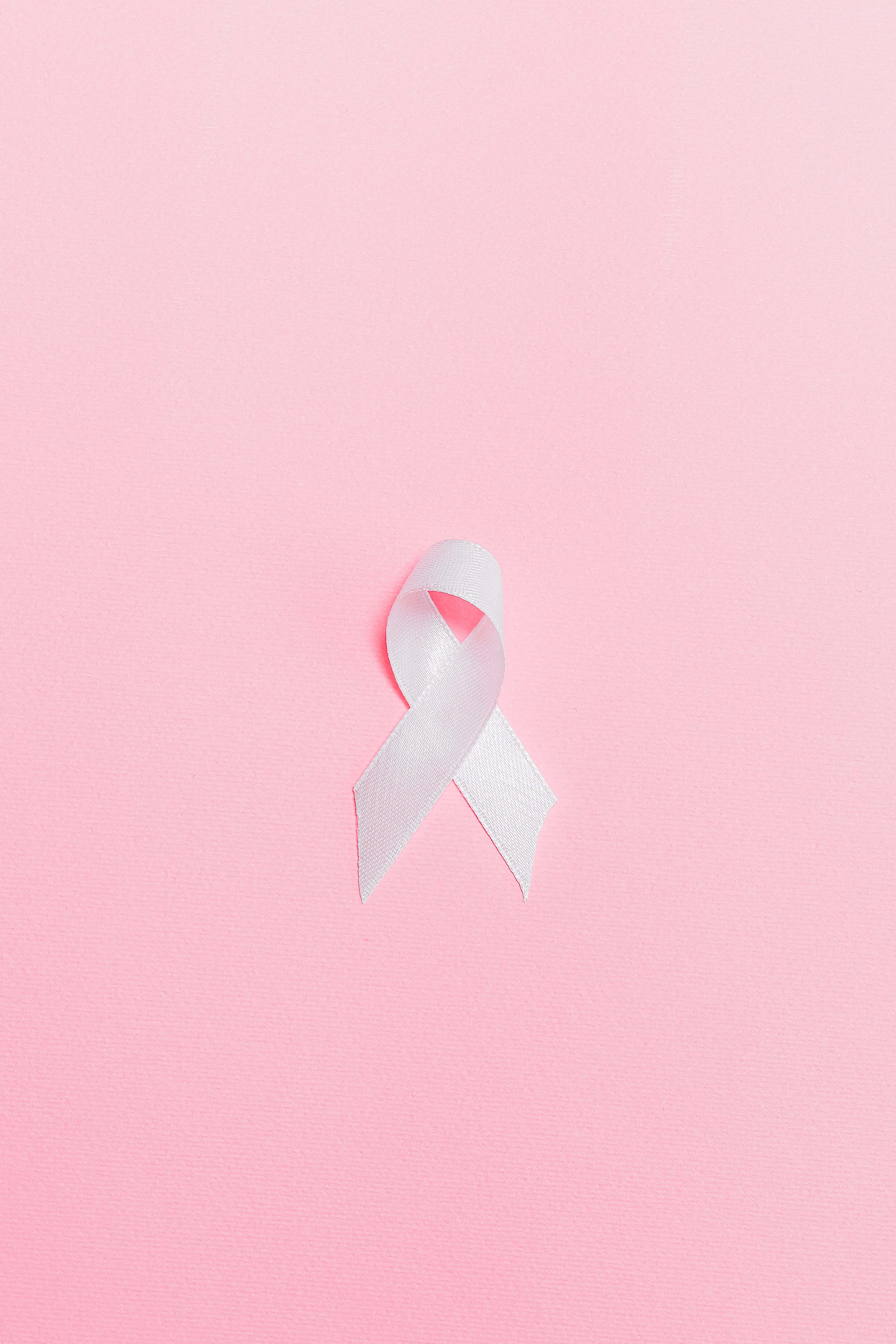 Aesthetic Baby Pink 桌布 壁紙 — 一條白色的意識絲帶居中放在柔軟的粉紅色紋理背景上。