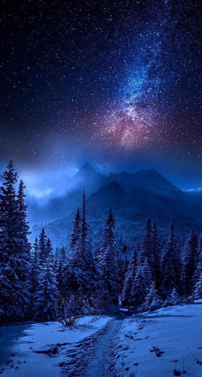 酷炫星系 桌布 壁紙 — 一條積雪森林小徑通往霧氣繚繞的山脈，上方是充滿活力的星空，銀河閃耀。