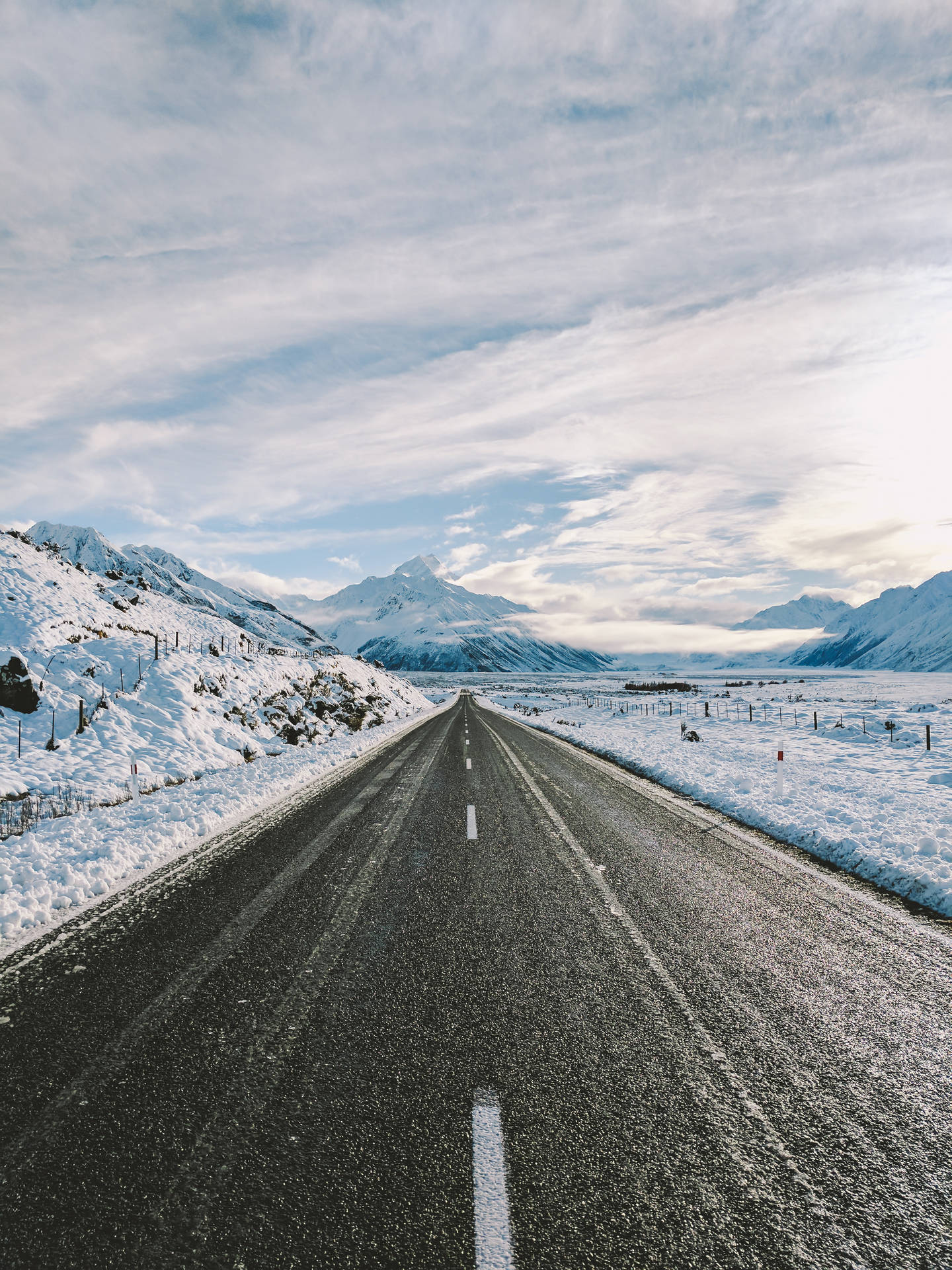 多雲天空下，積雪的山路延伸至遠方。 — Google pixel 壁紙