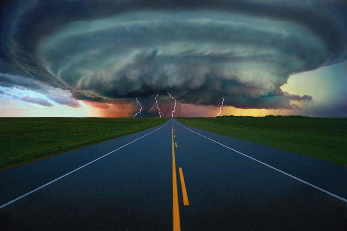 Weather 桌布 壁紙 — 一條筆直的柏油道路伸向巨大的暴風雲，閃電在黃昏時分擊中草地平原。