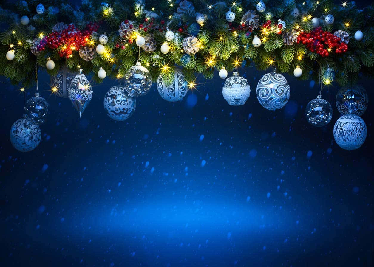 Christmas Party 桌布 壁紙 — 一條節日聖誕花環，帶有藍色裝飾、紅色漿果和閃爍的燈光，掛在雪白的藍色夜空下。