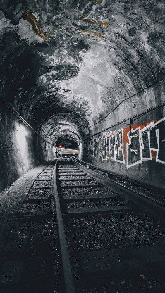 train tunnel 桌布 壁紙 — 一條粗糙的鐵路隧道，牆壁佈滿塗鴉，路軌通向盡頭的遠處光線。