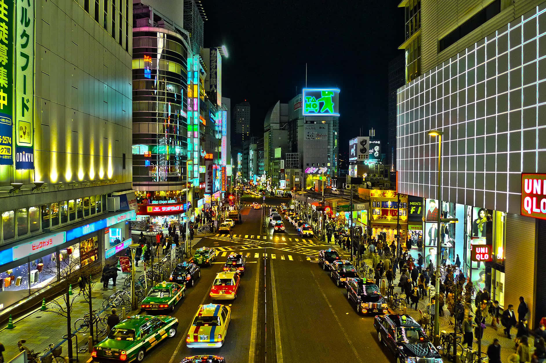 東京 桌布 壁紙 — 一條繁忙的城市街道，充滿閃爍的霓虹燈招牌和人群，構成耀眼的夜景。