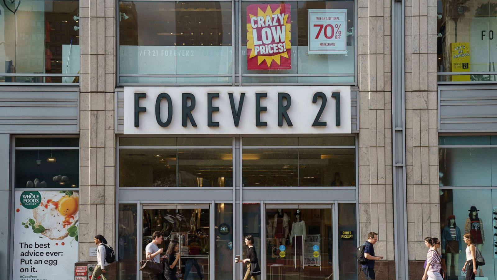 永遠21 桌布 壁紙 — 一條繁忙的城市街道上有一間Forever 21商店，帶有醒目的招牌，購物者經過展示人體模型和促銷海報的玻璃櫥窗。