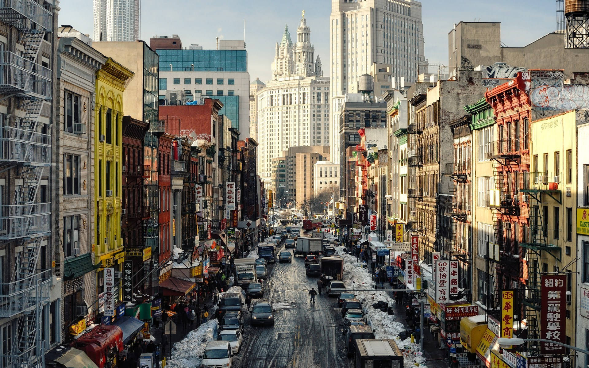 Nyc 桌布 壁紙 — 一條繁忙的雪景城市街道，兩旁是色彩繽紛的建築物和高聳的摩天大樓，頭頂是清澈的藍天。