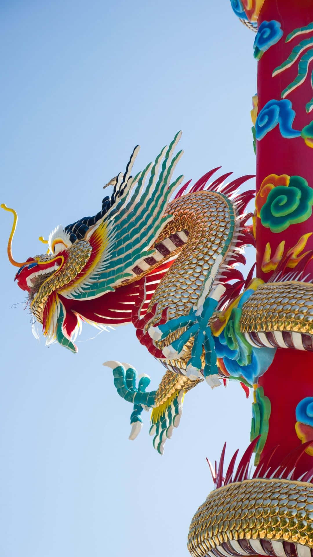 Blue Dragon 桌布 壁紙 — 一條色彩鮮豔、細節精緻的中國龍雕塑纏繞在紅色柱子上，背景是清澈的藍天。