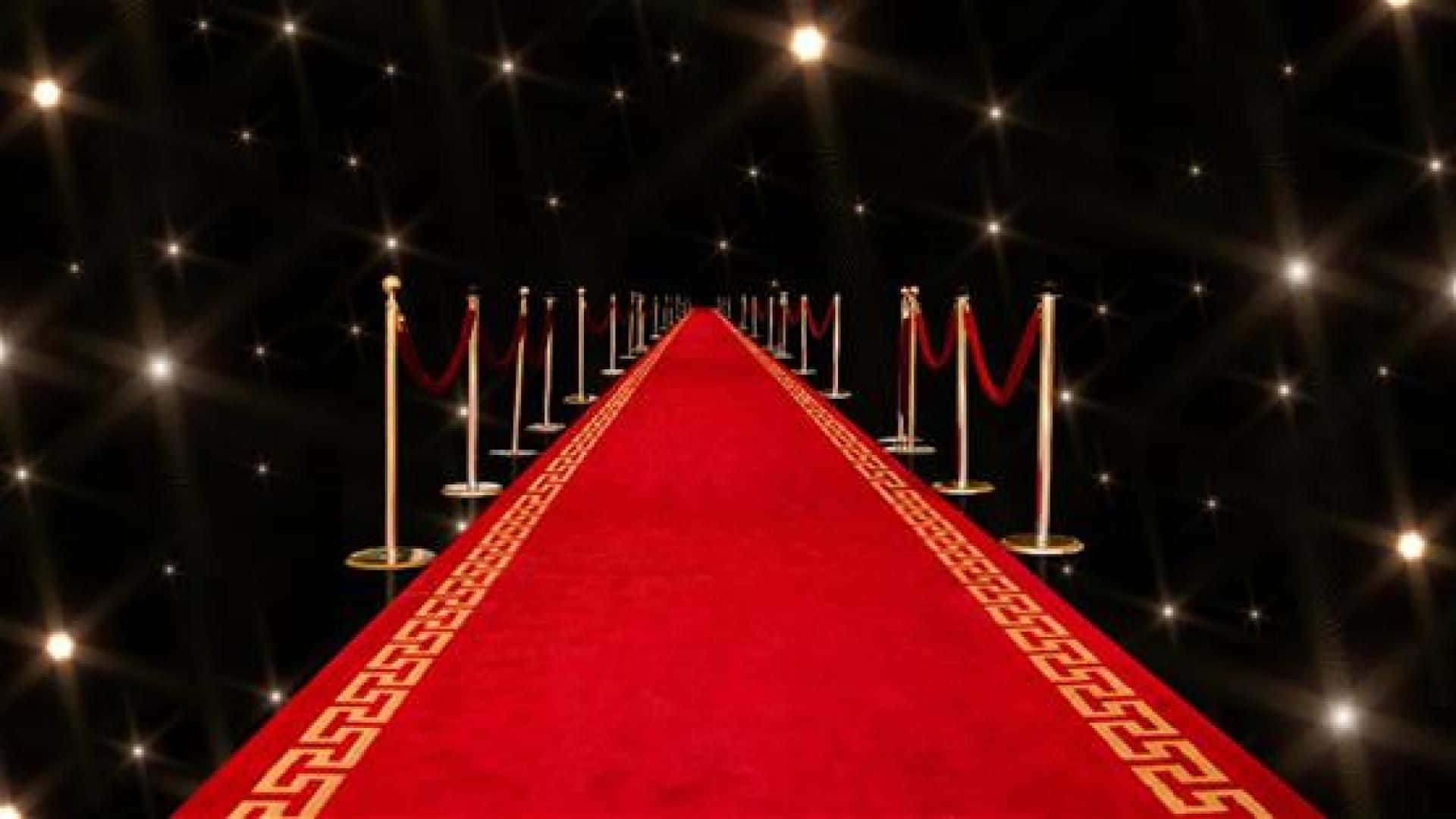 Red Carpet 桌布 壁紙 — 一條華麗的紅地毯，帶有金色飾邊，在黑色背景下閃爍的燈光中延伸至遠方。