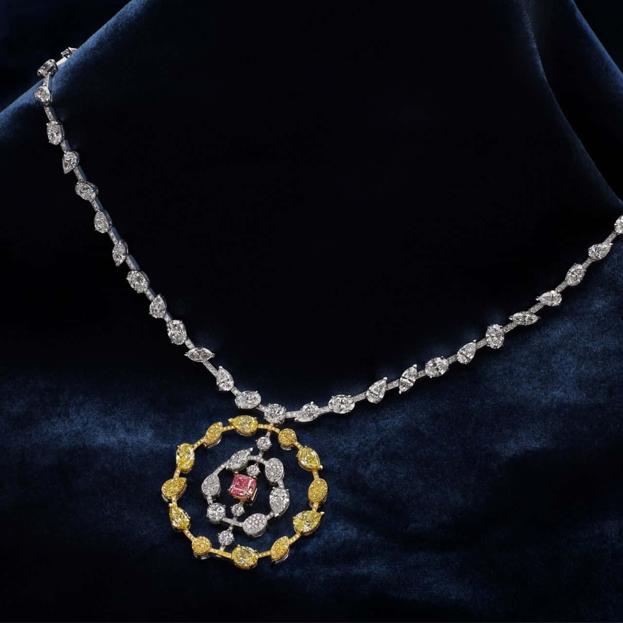 Gem Stone 桌布 壁紙 — 一條華麗的鑽石項鍊，中央鑲有粉紅色寶石和黃金點綴，優雅地放置在深藍色天鵝絨上。