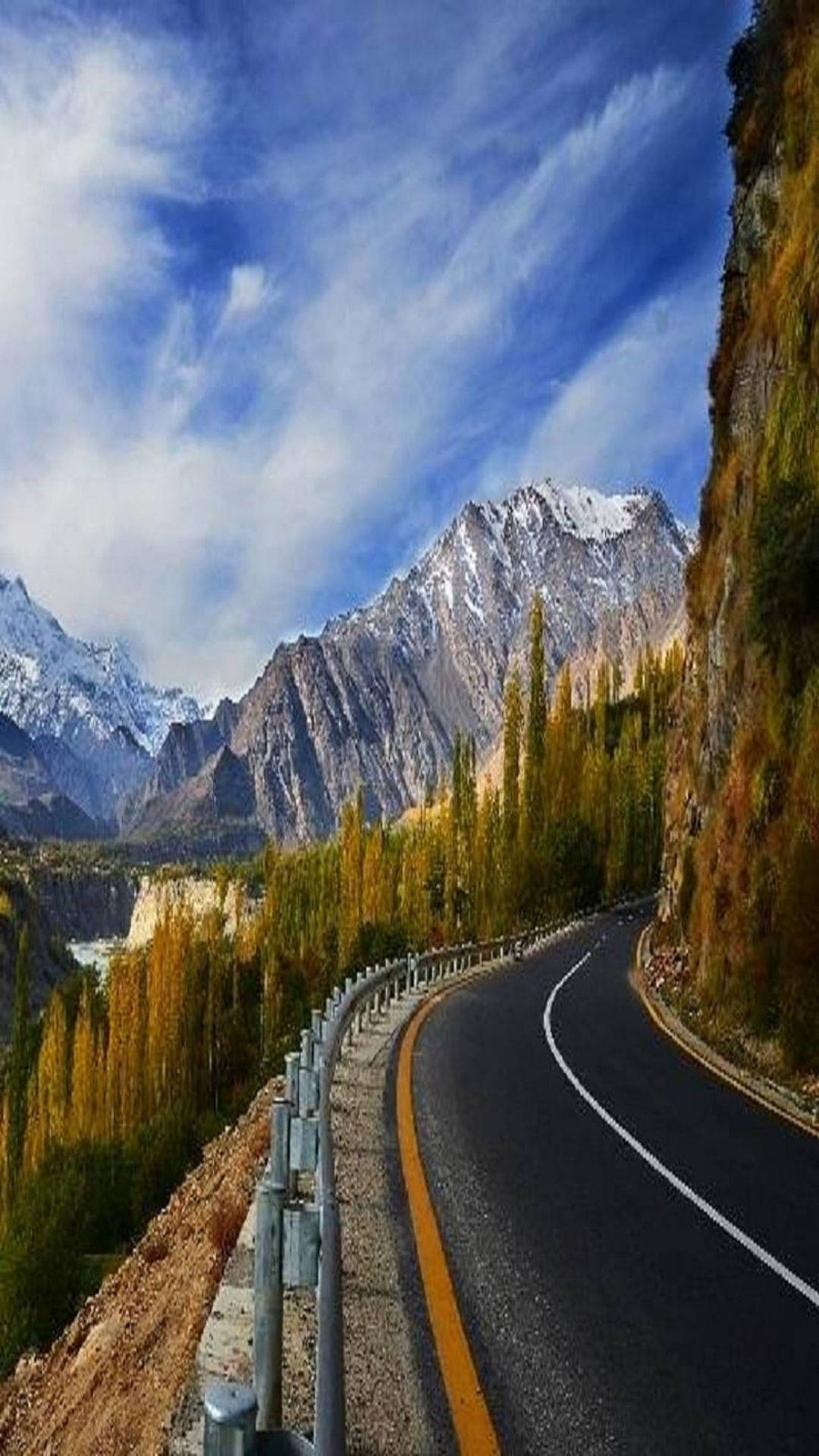Pakistan 桌布 壁紙 — 一條蜿蜒的山路穿過秋日森林，在湛藍的天空下，雪峰聳立。