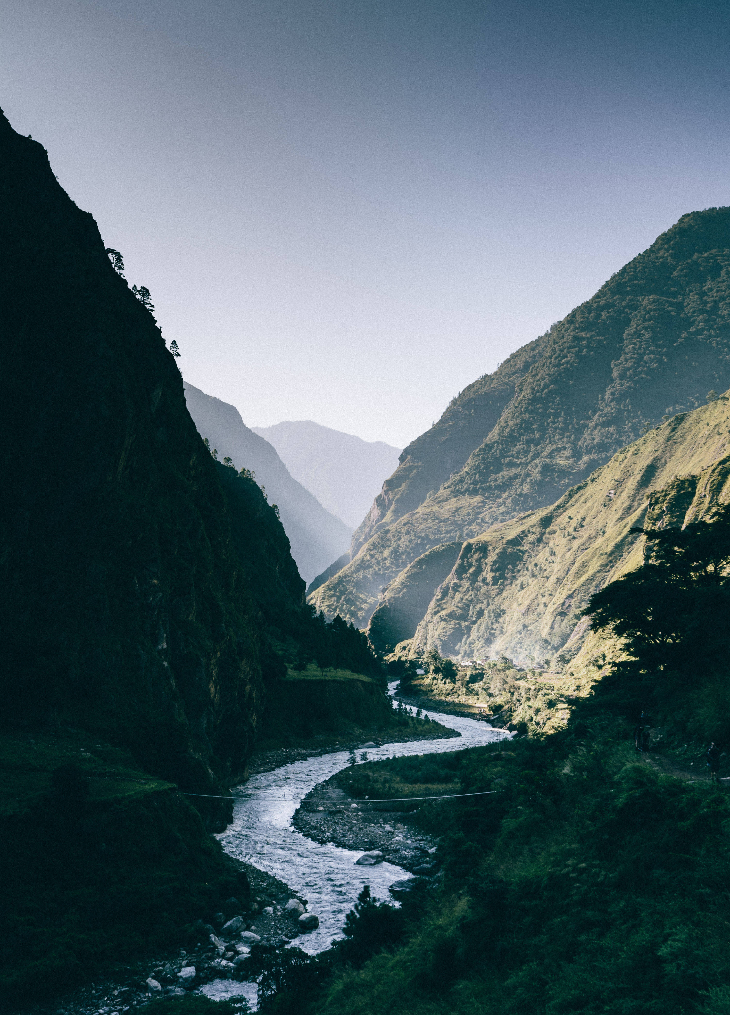 Nepal 桌布 壁紙 — 一條蜿蜒的河流在柔和的藍天下穿過深綠色的山谷。